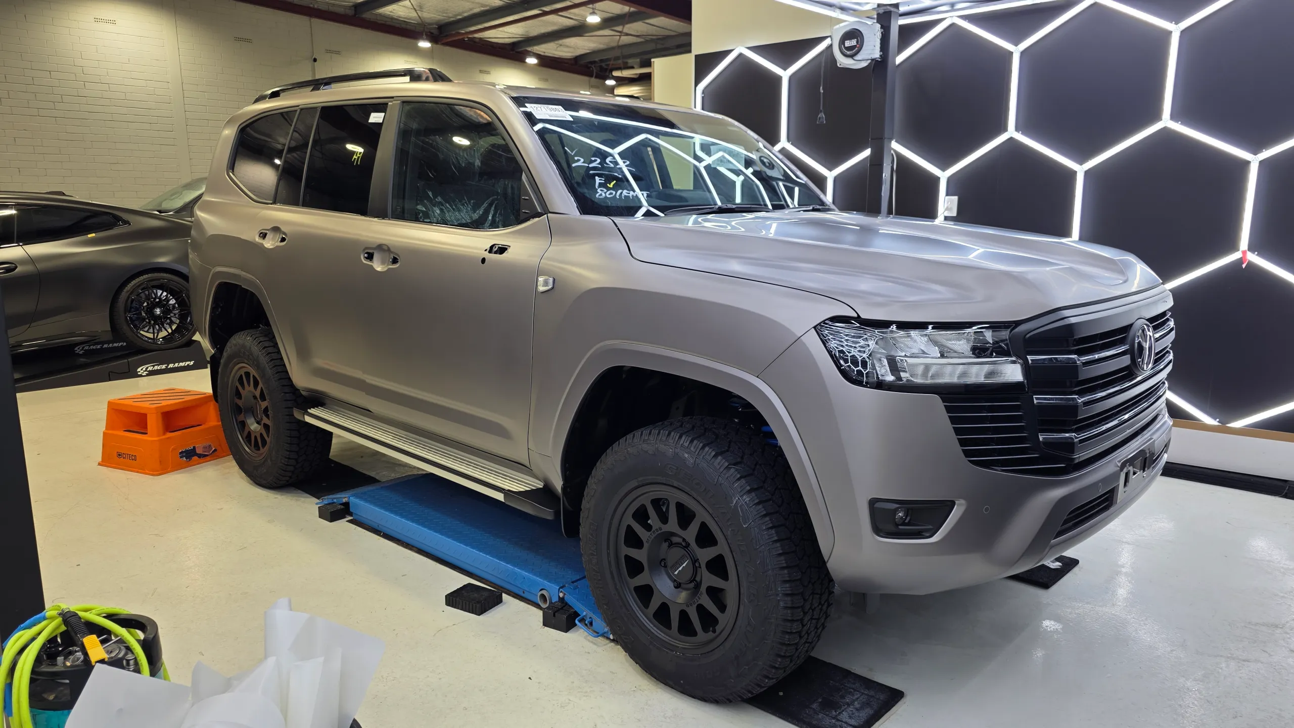 Satin bronze-grey Toyota LandCruiser 300 during wrapping with door handles removed