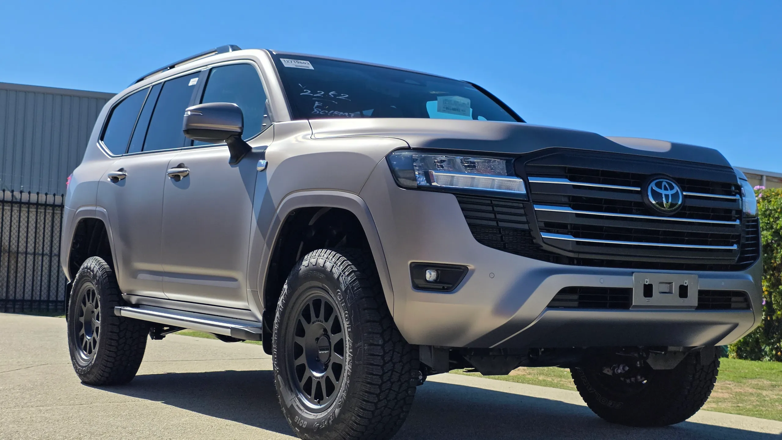 Satin bronze-grey Toyota LandCruiser 300 viewed from the front quarter outdoors