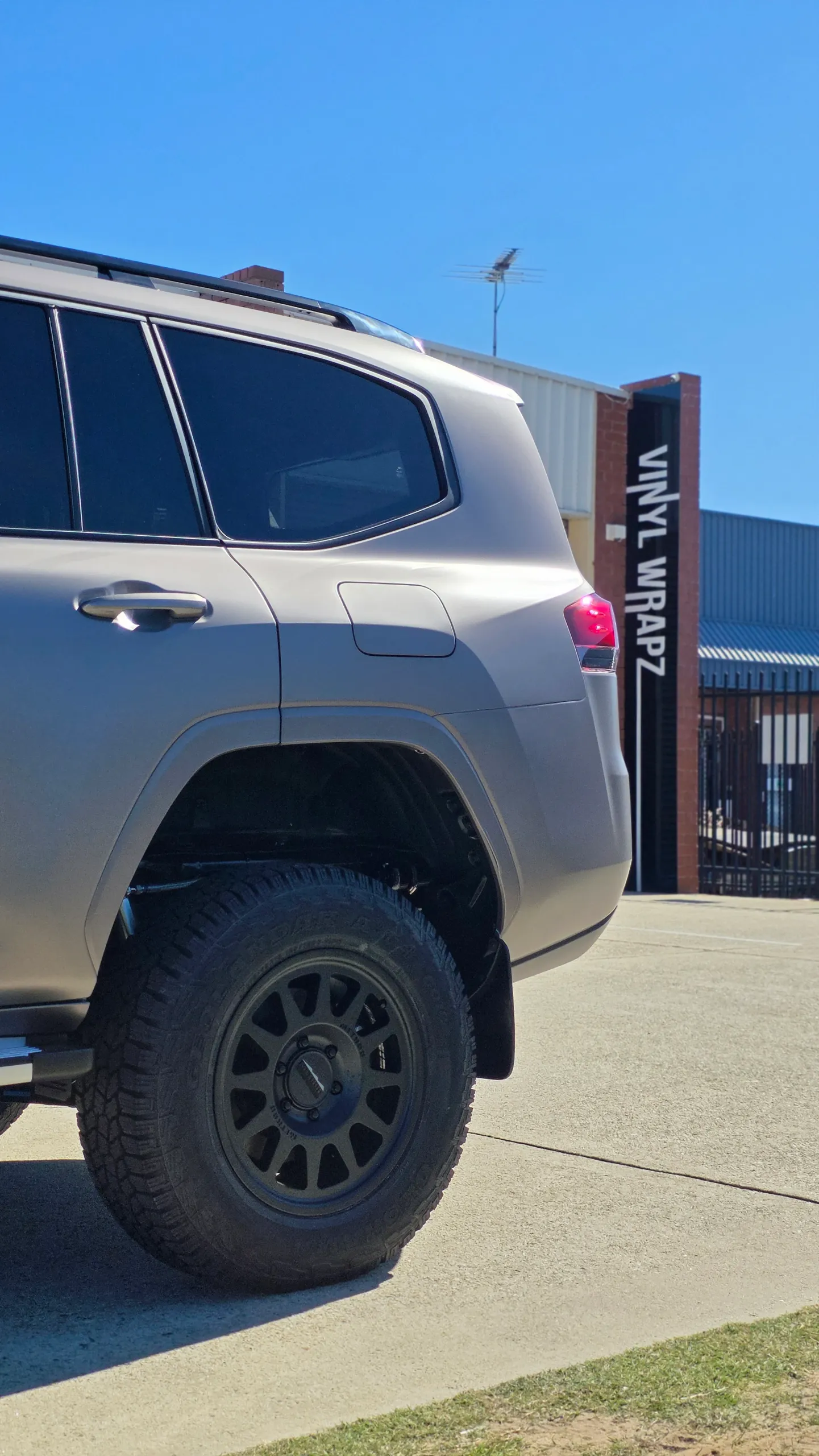 Satin bronze-grey finish across the LandCruiser 300 rear door and wheel arch