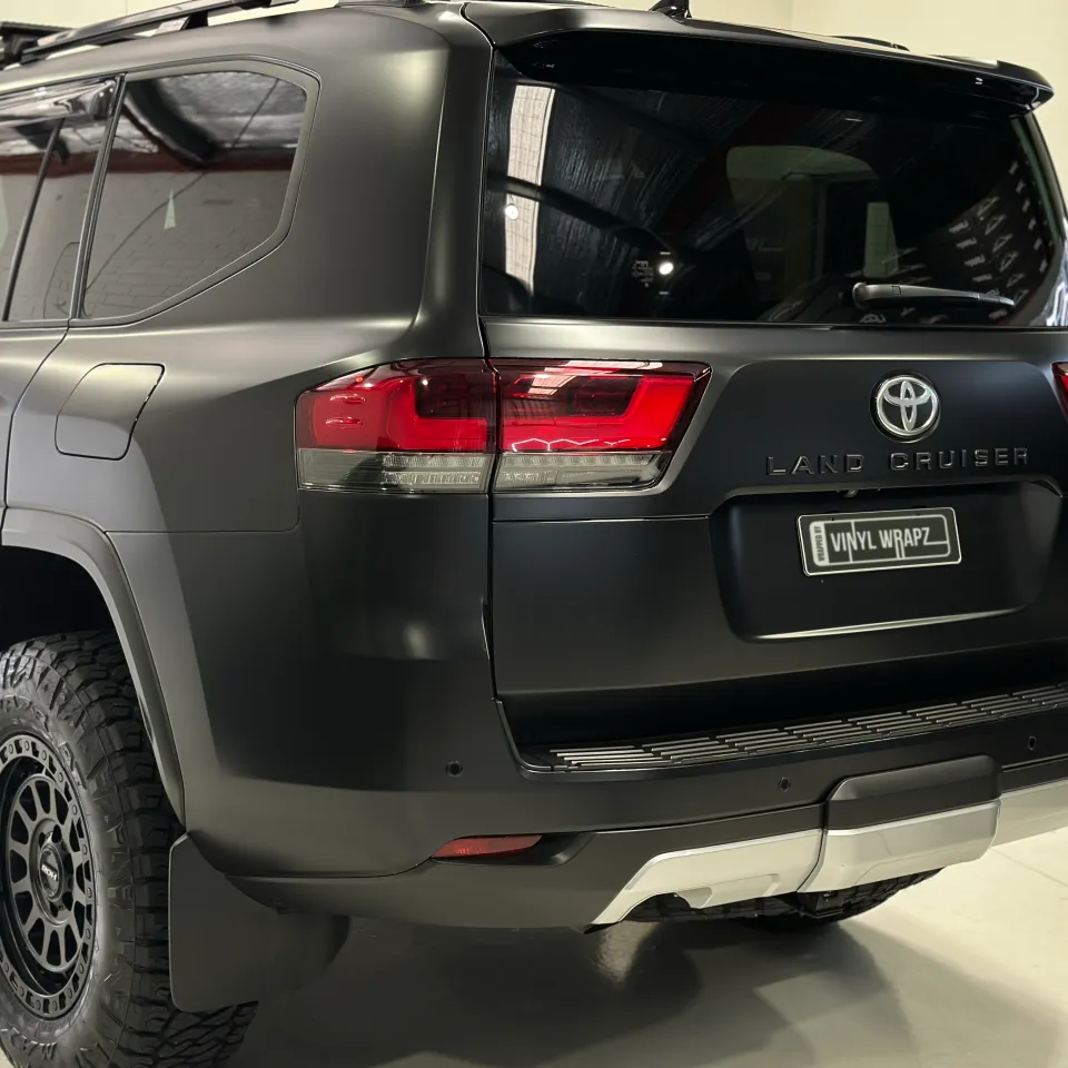 Rear-quarter view of the matte black Toyota LandCruiser 300 in the workshop