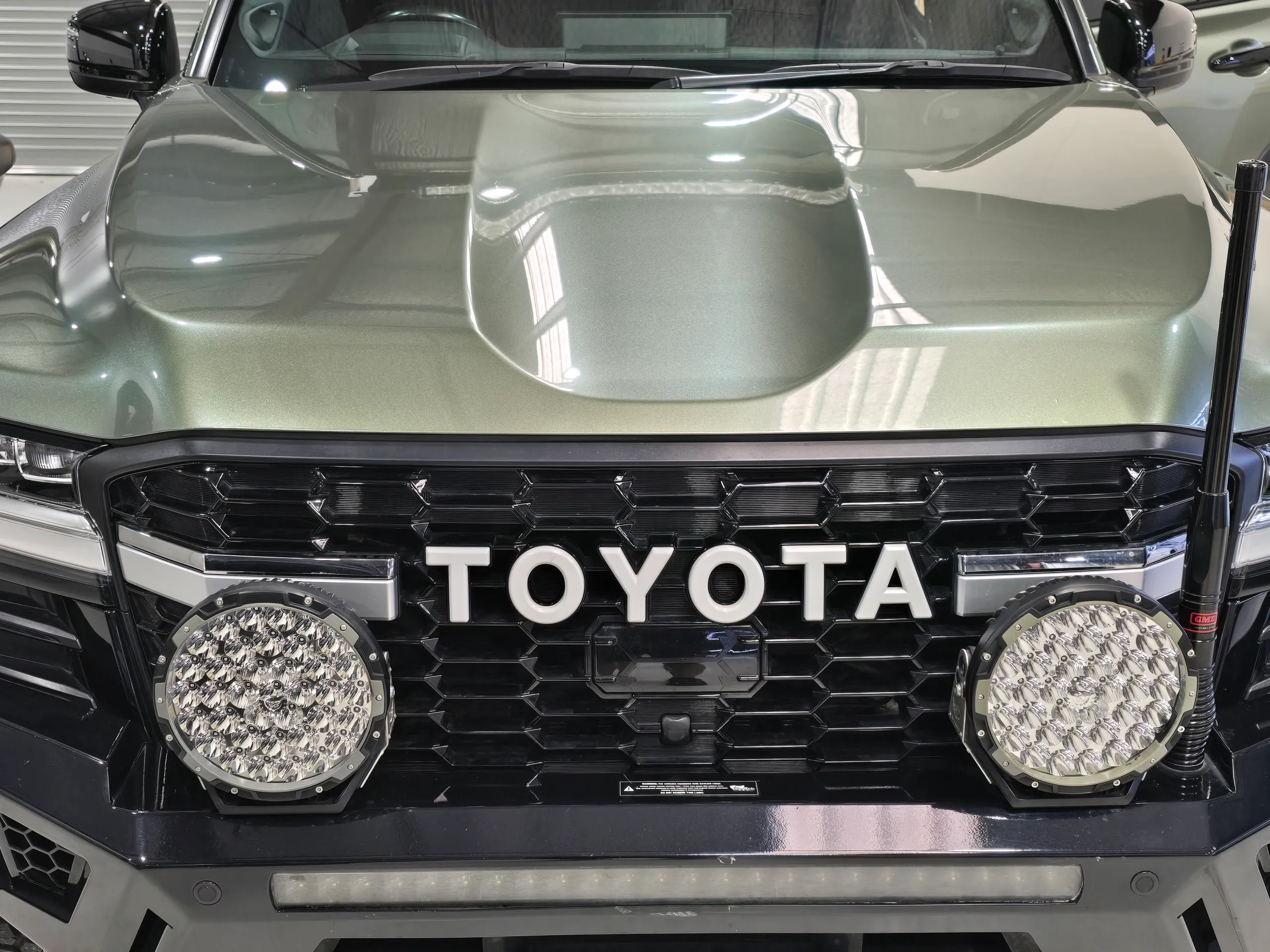 Green LandCruiser bonnet above the Toyota grille and round driving lights