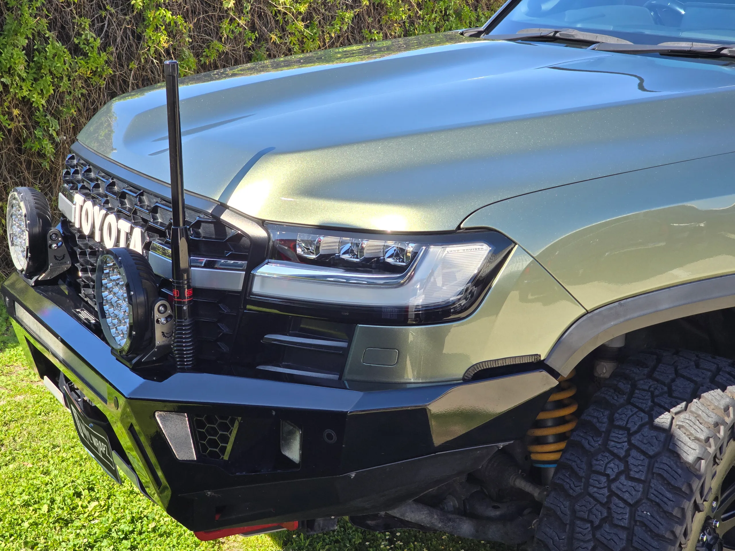 Metallic green LandCruiser bonnet, headlight and front bar in sunlight