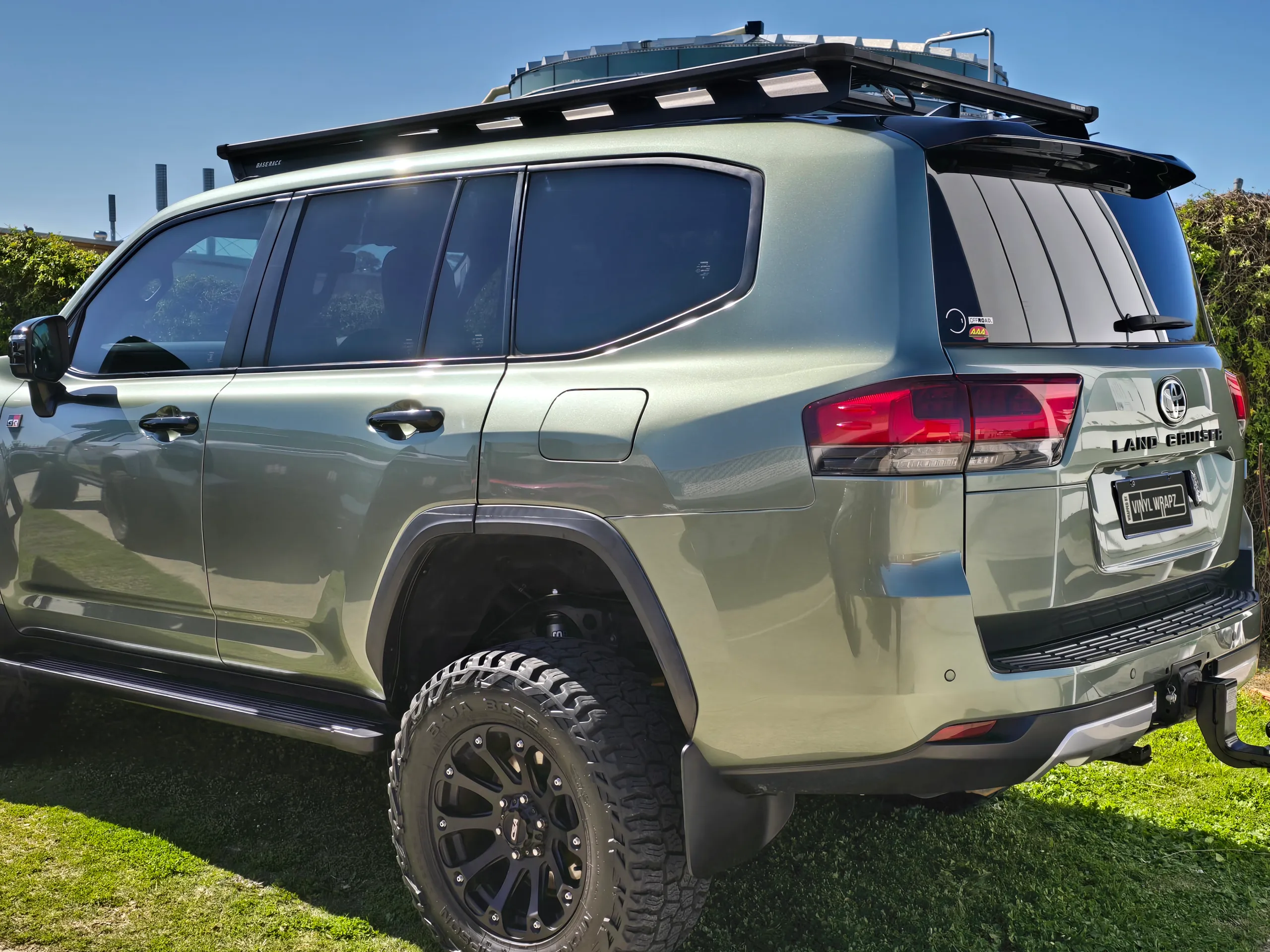Green LandCruiser rear quarter with a roof rack and off-road tyres outdoors