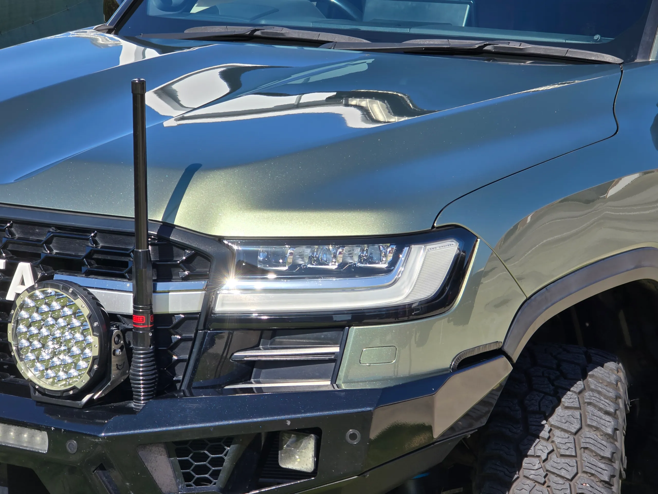 Close view of the green LandCruiser headlight, bonnet and driving light outside