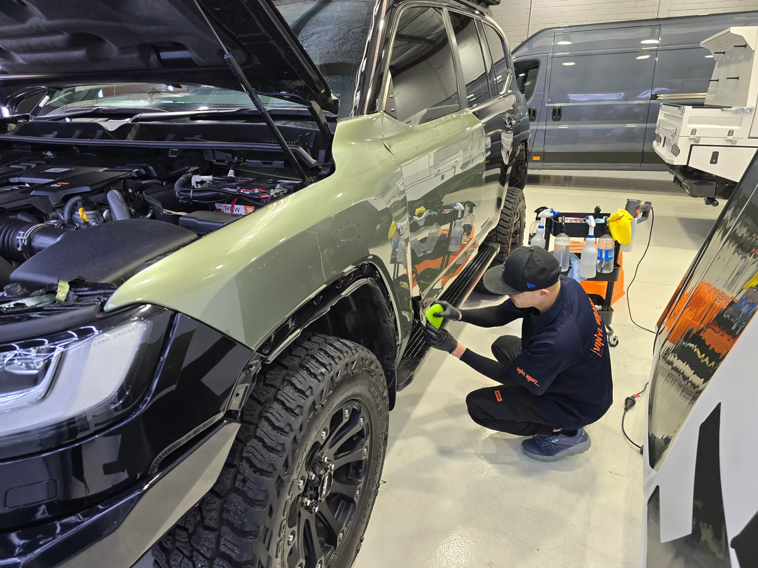 Installer smoothing green film around the LandCruiser front wheel arch