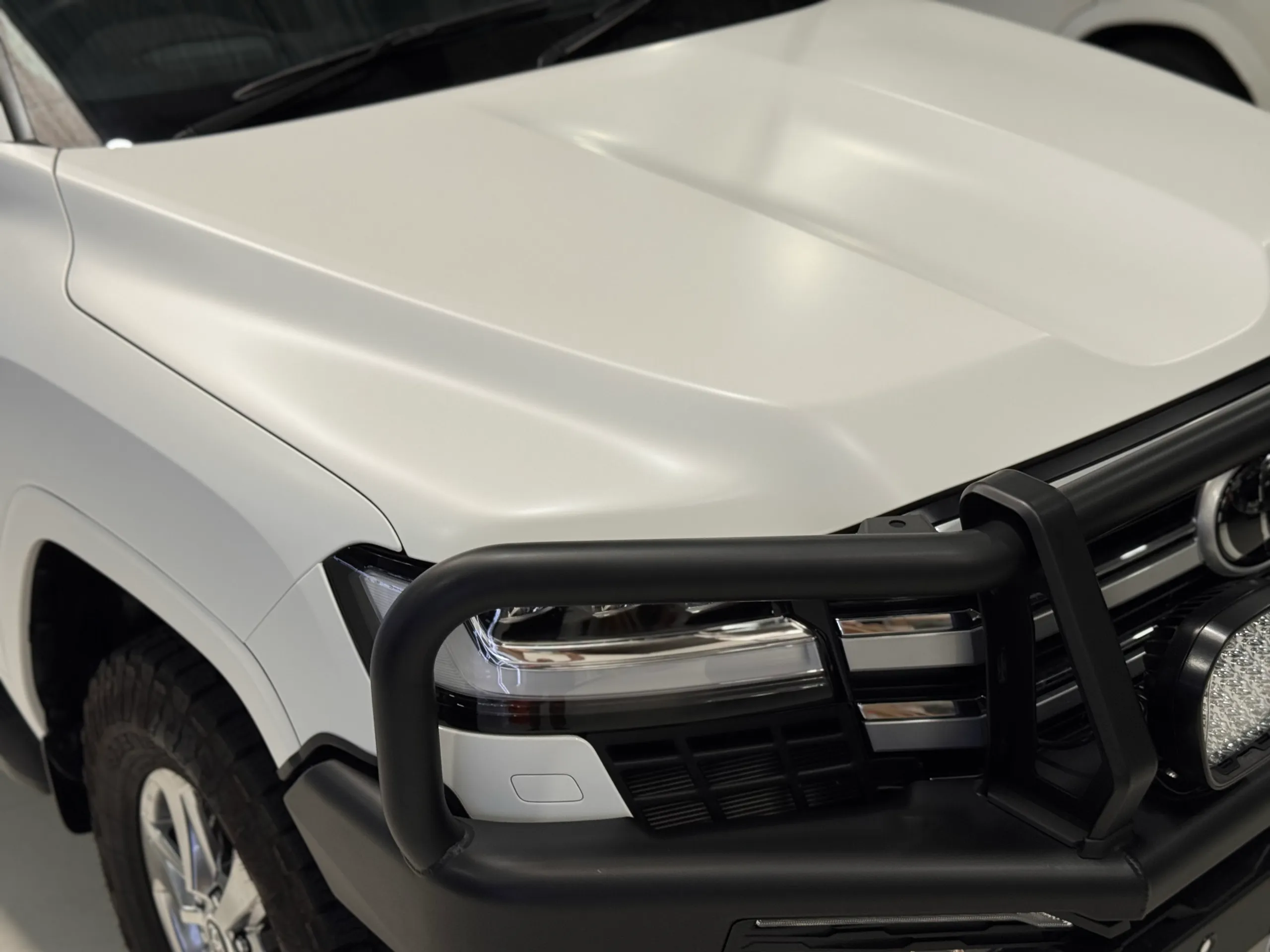 Matte white LandCruiser 300 bonnet and front guard above a black bull bar