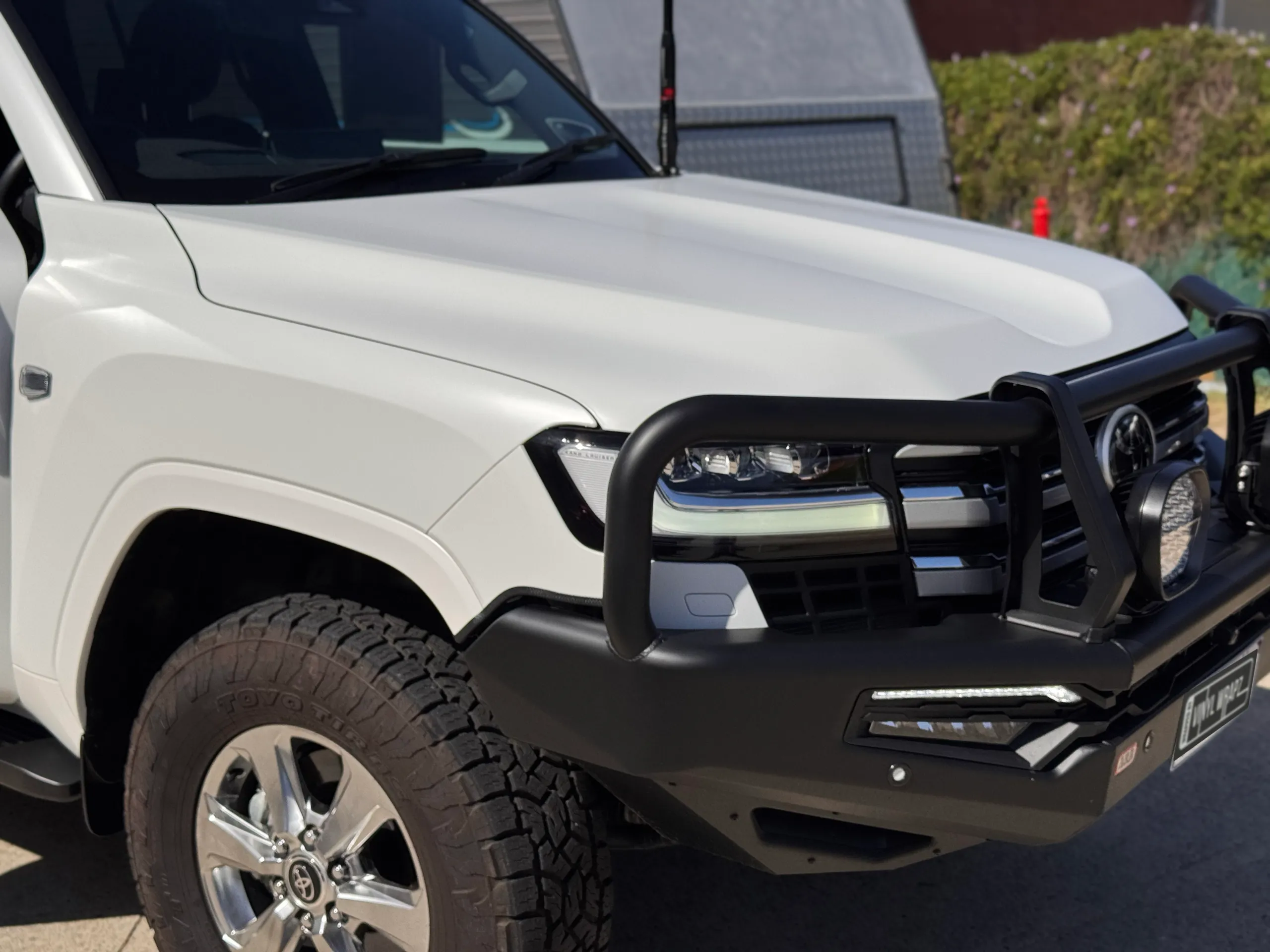 Matte white LandCruiser 300 front guard and black bull bar outdoors