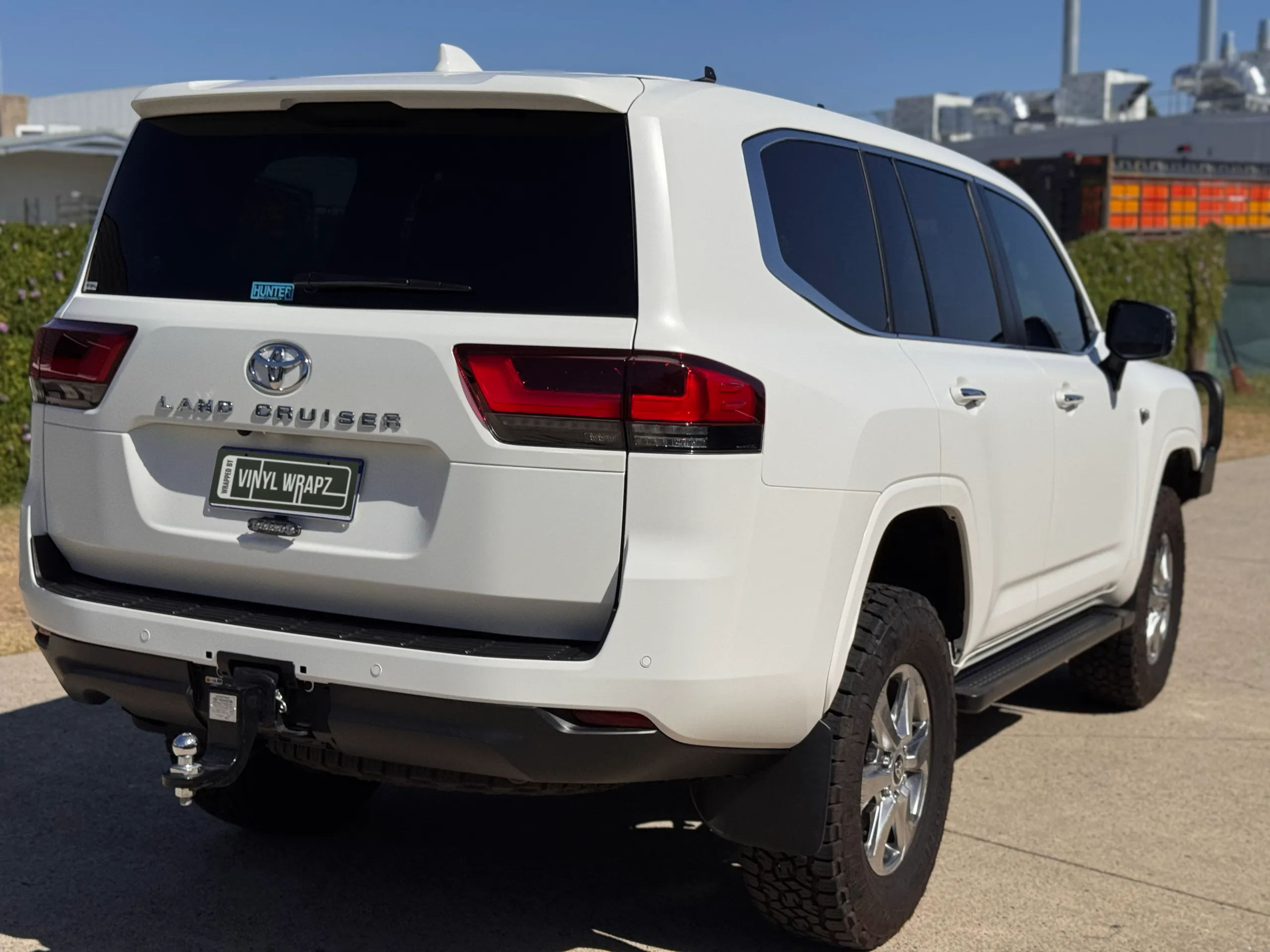 Rear-quarter view of the matte white Toyota LandCruiser 300 outside the workshop