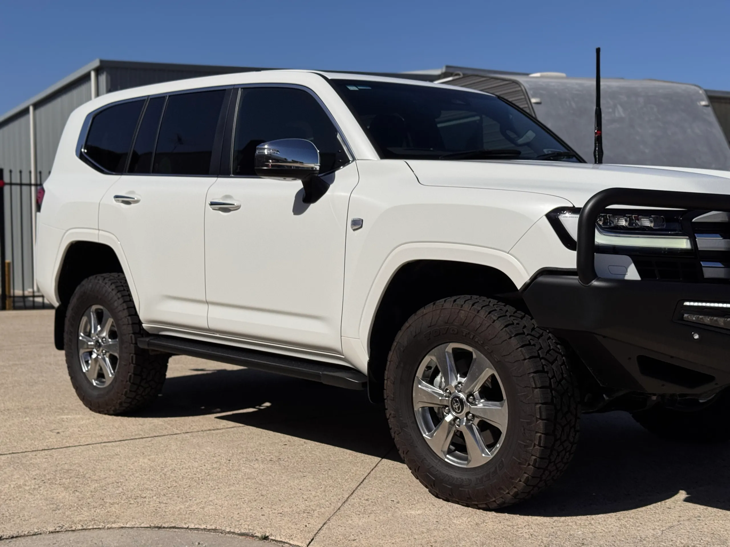 White Toyota LandCruiser 300 doors and front wheel beneath dark side windows