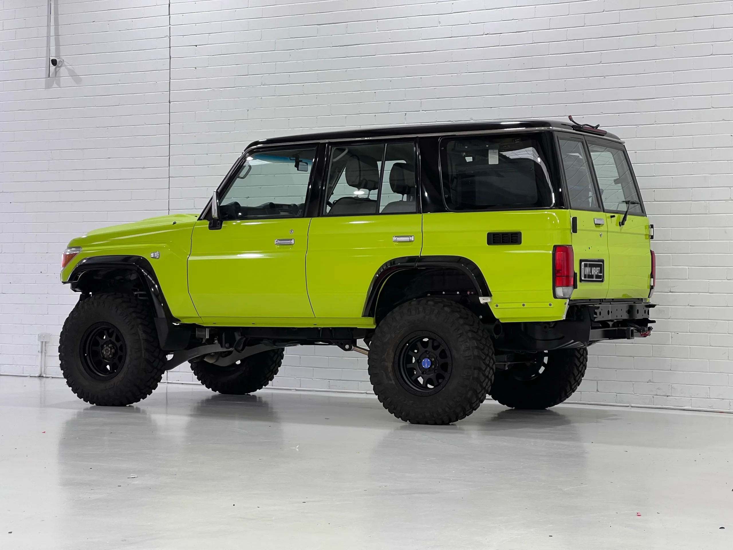 Lime green and black Toyota LandCruiser 76 Series, rear quarter
