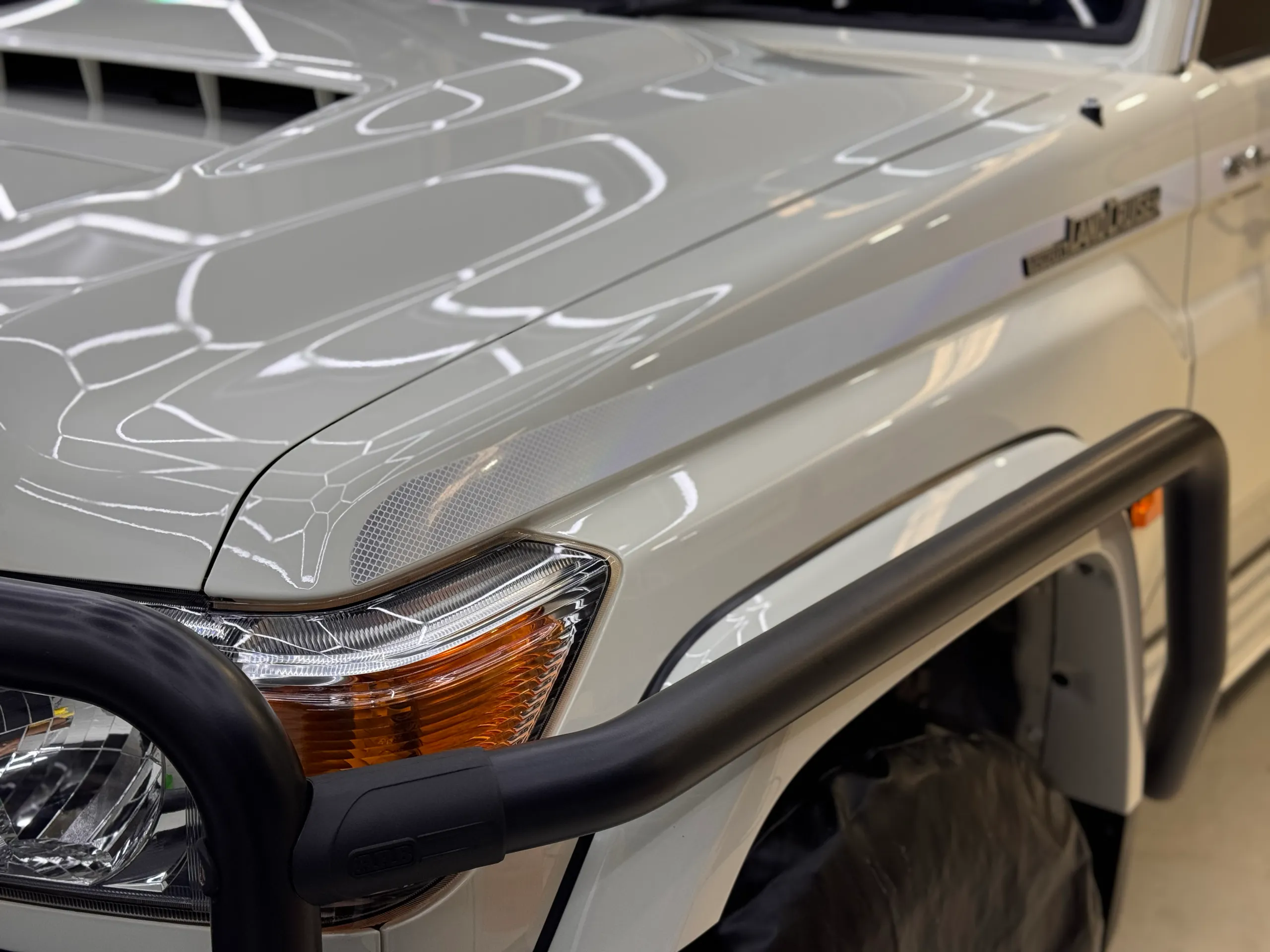Gloss white LandCruiser bonnet and front guard beside a black brush bar