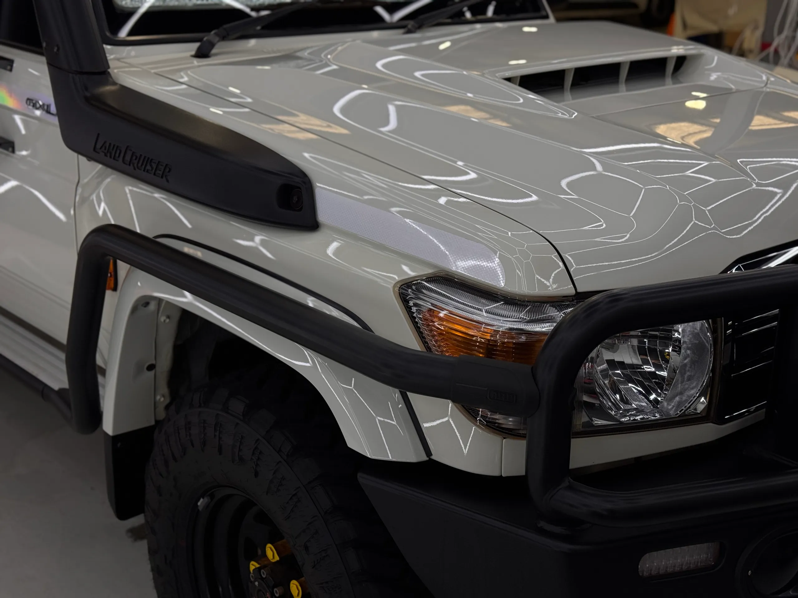 White LandCruiser front corner showing its snorkel, bonnet scoop and bullbar
