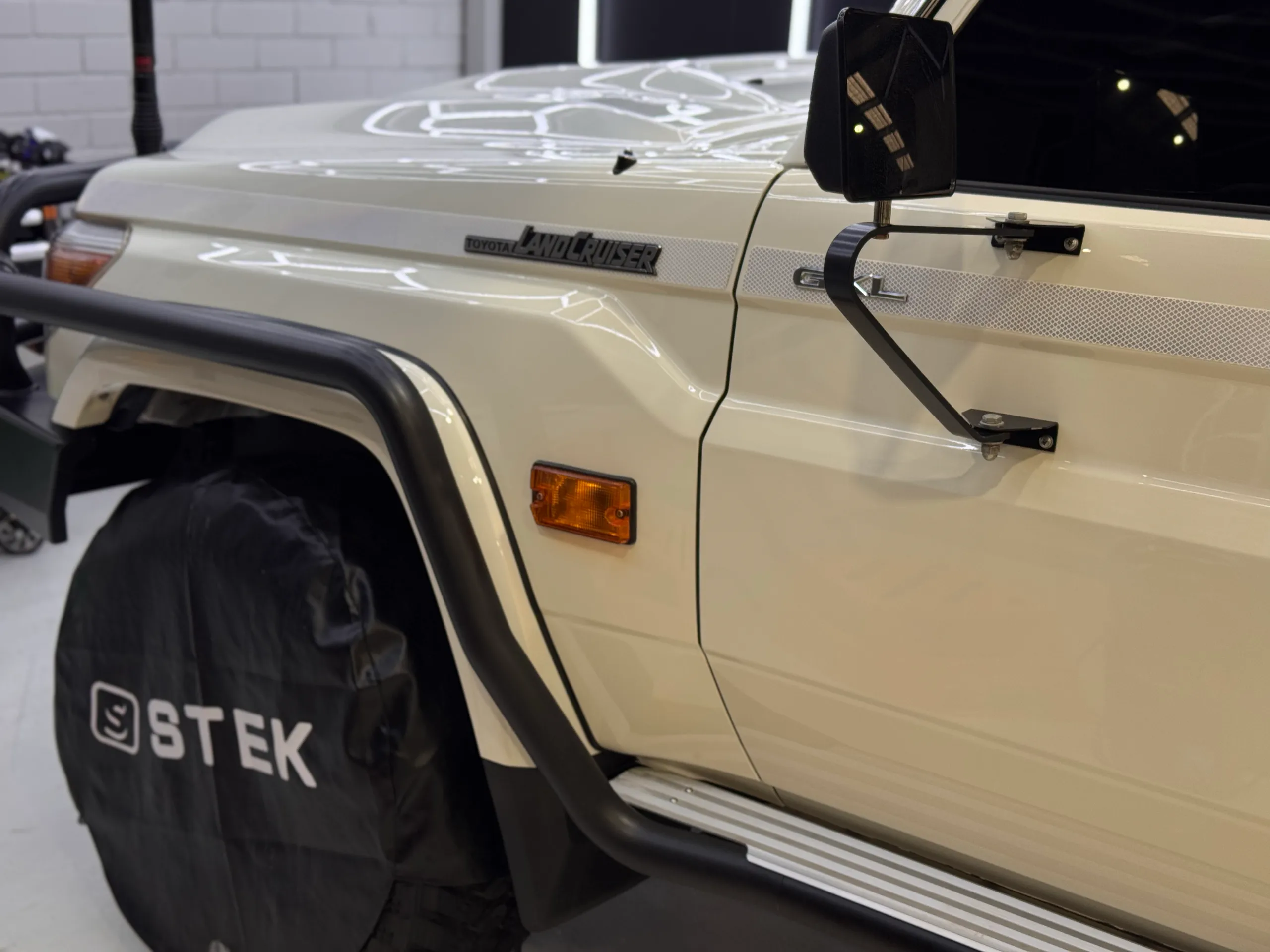 White LandCruiser guard and front door with the wheel covered in the workshop