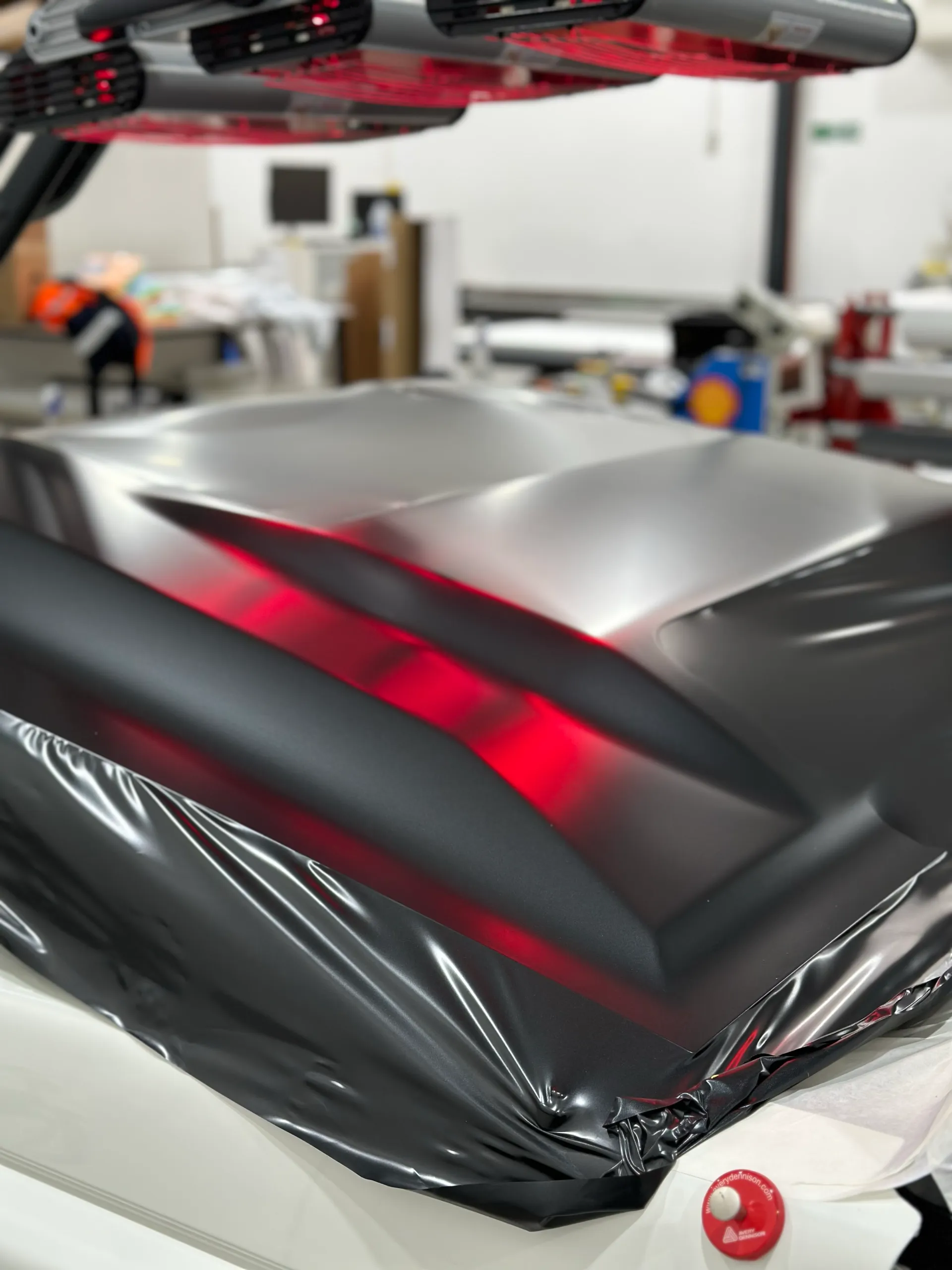 Loose dark film across the LandCruiser bonnet beneath workshop heat lamps