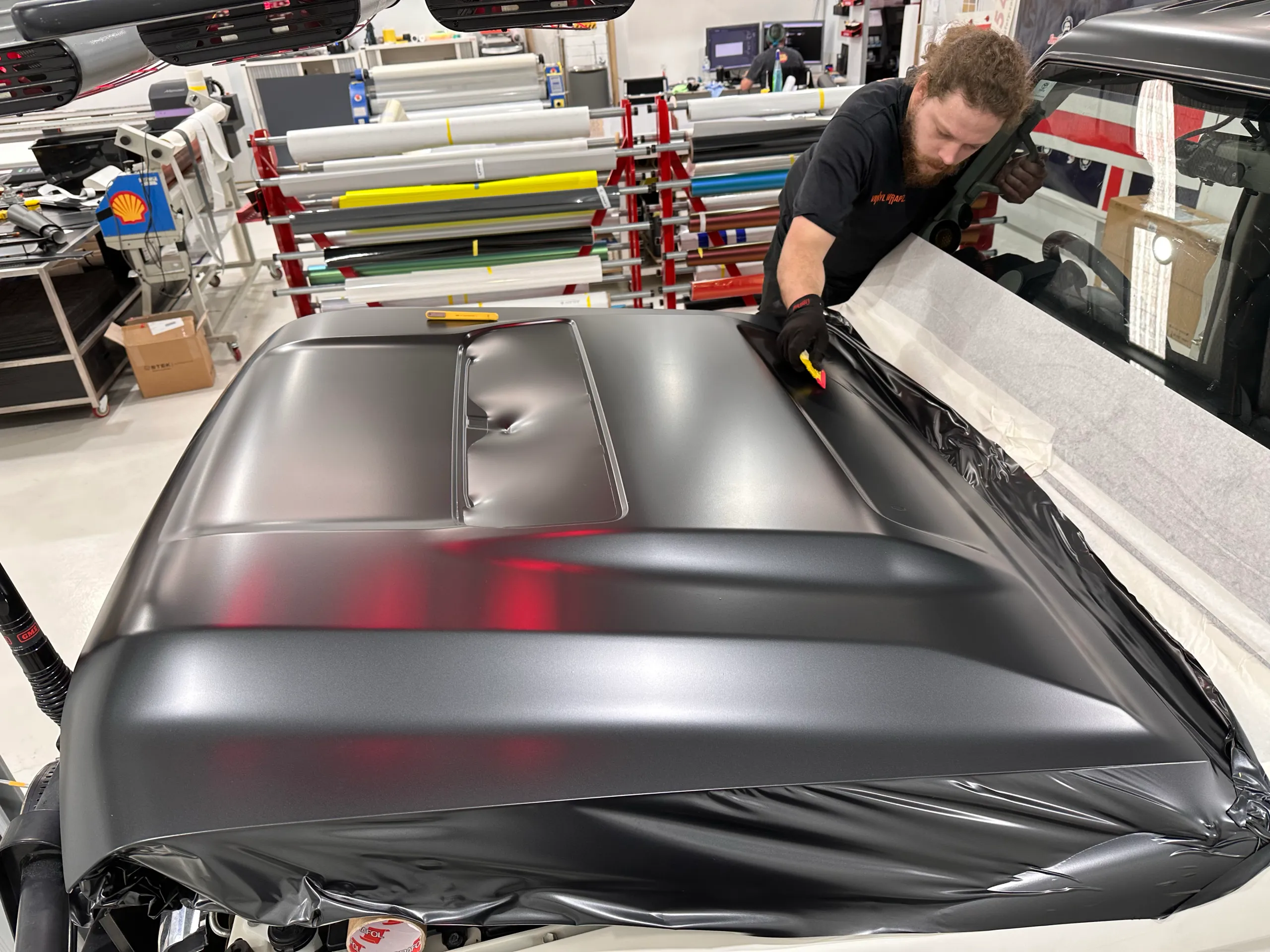 Installer fitting dark film across the LandCruiser bonnet