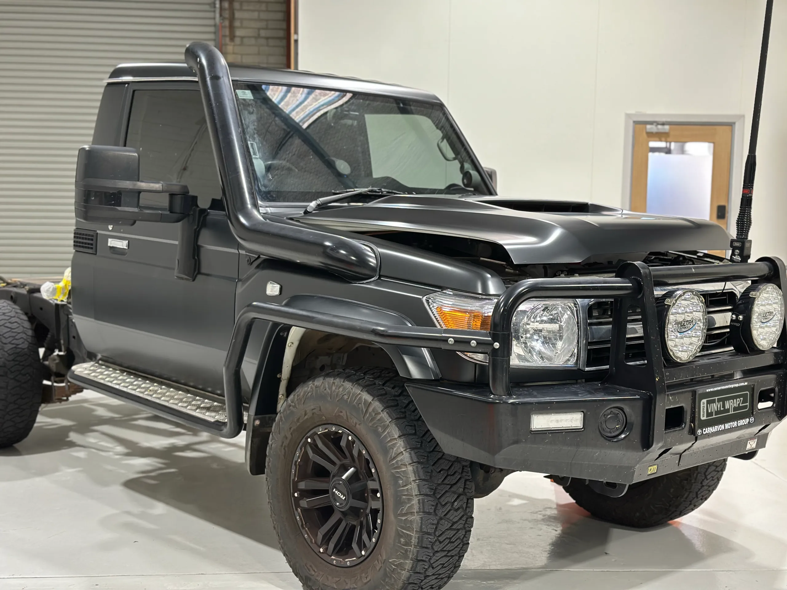 Dark grey LandCruiser single cab in the workshop with its bonnet ajar