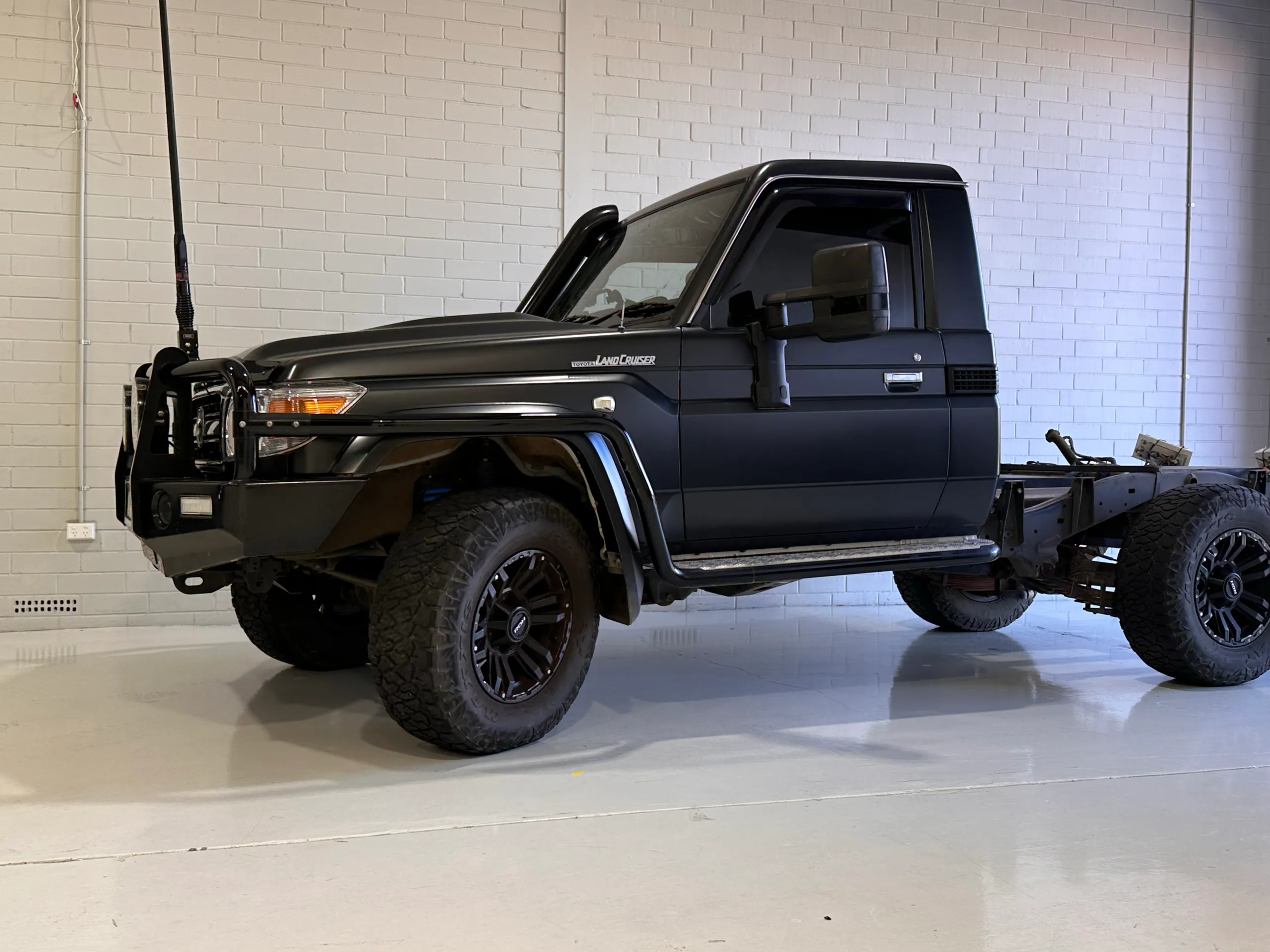 Dark grey Toyota LandCruiser 79 single cab and rear chassis inside the workshop