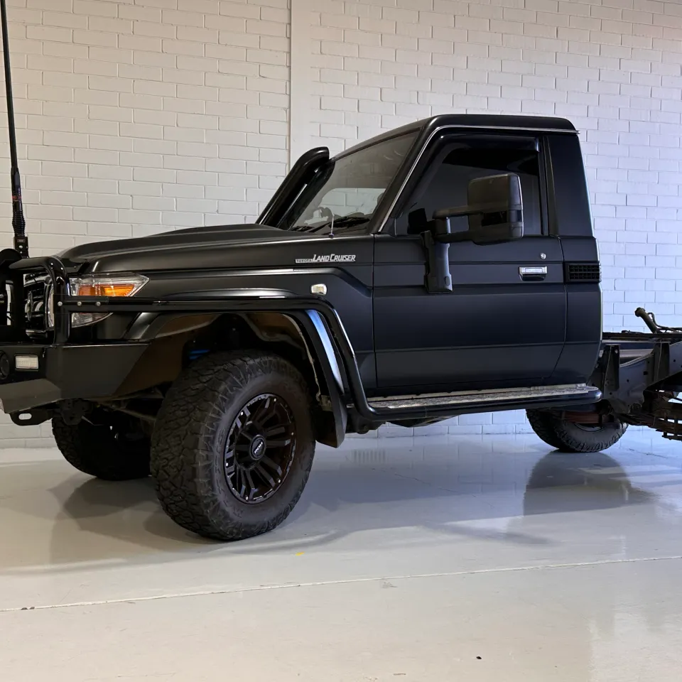 Dark grey Toyota LandCruiser 79 single cab and rear chassis inside the workshop