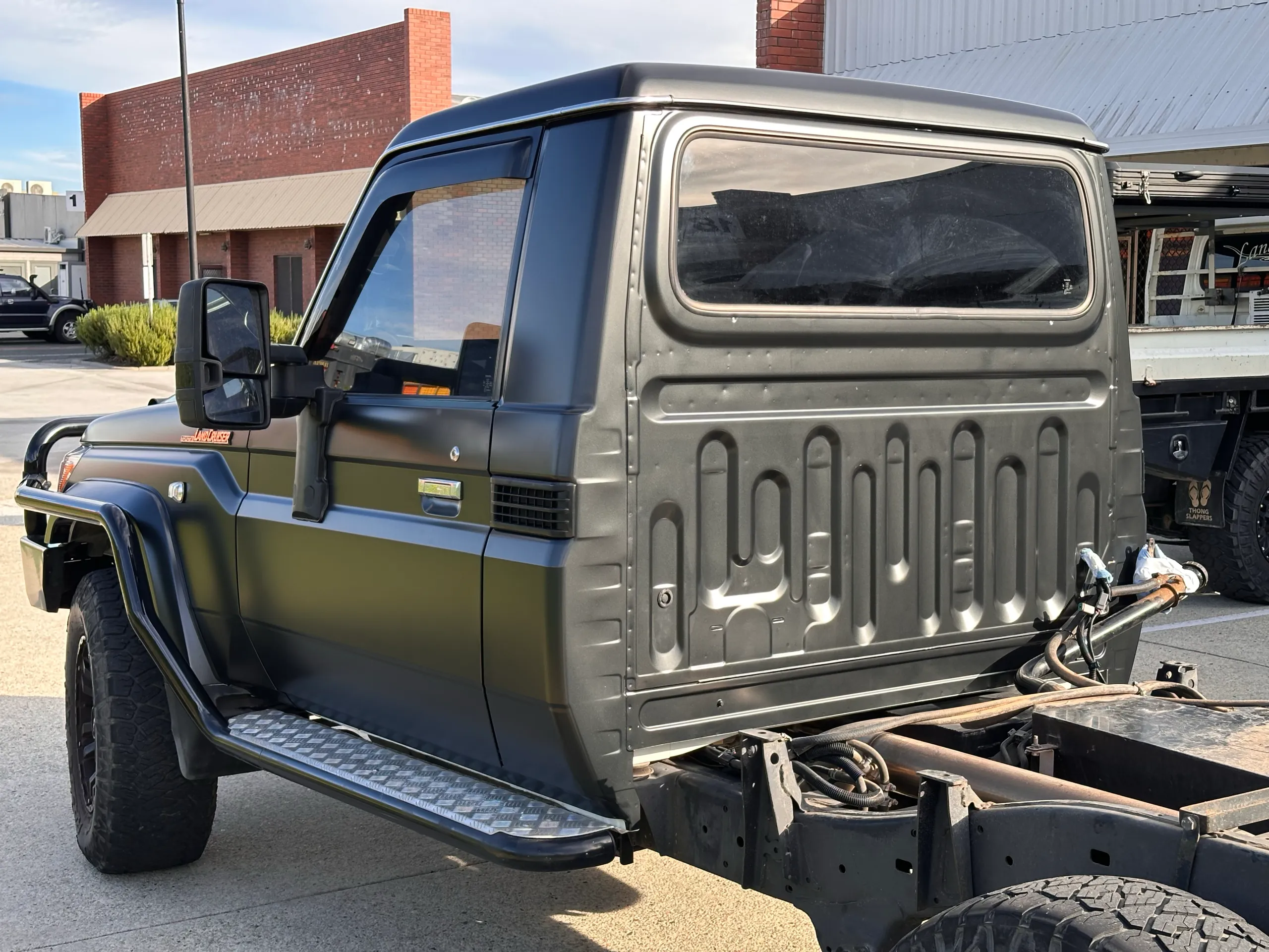 Rear of the dark grey LandCruiser single cab with its chassis exposed outdoors