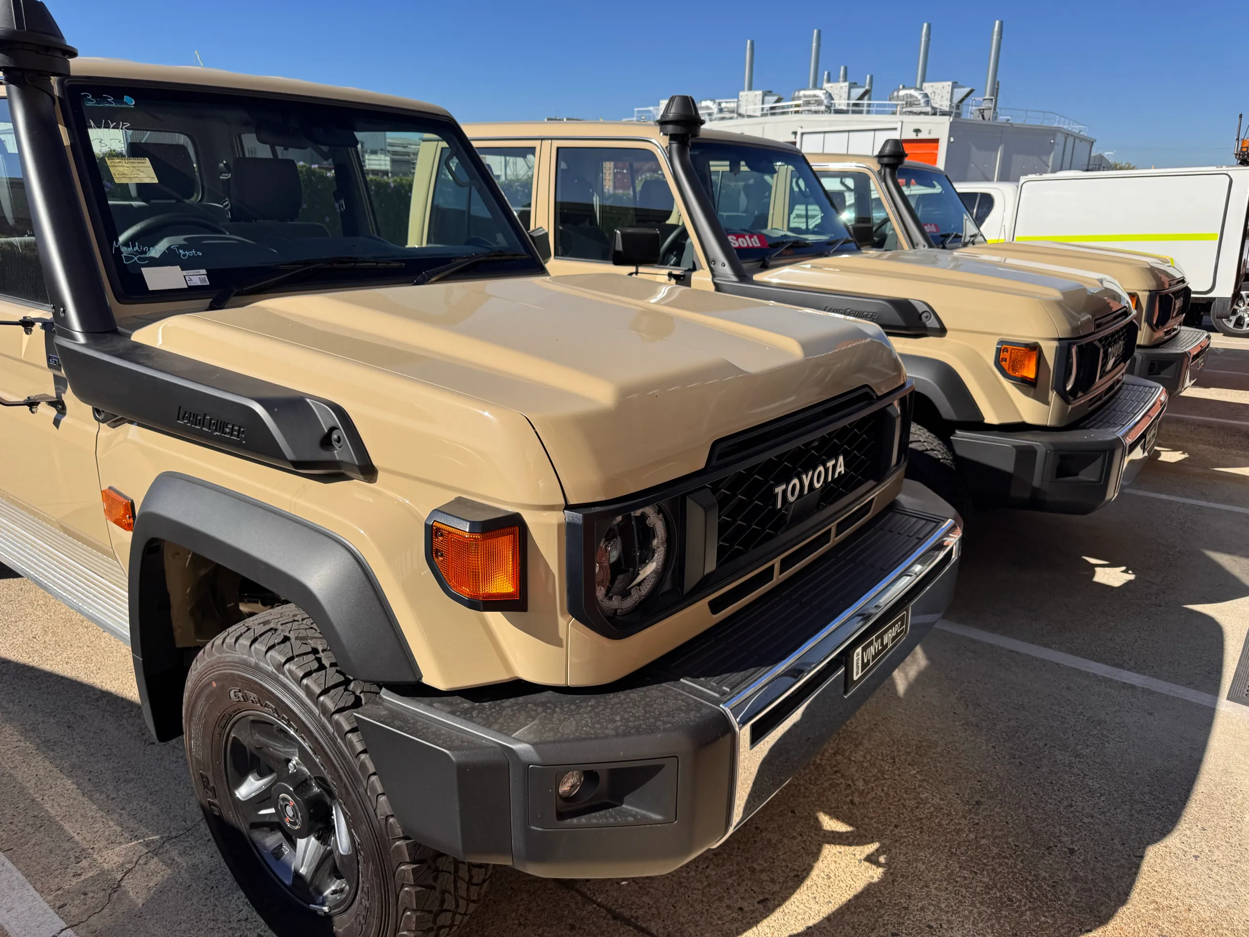 Tan Toyota LandCruiser 79 vehicles lined up before their colour-change work