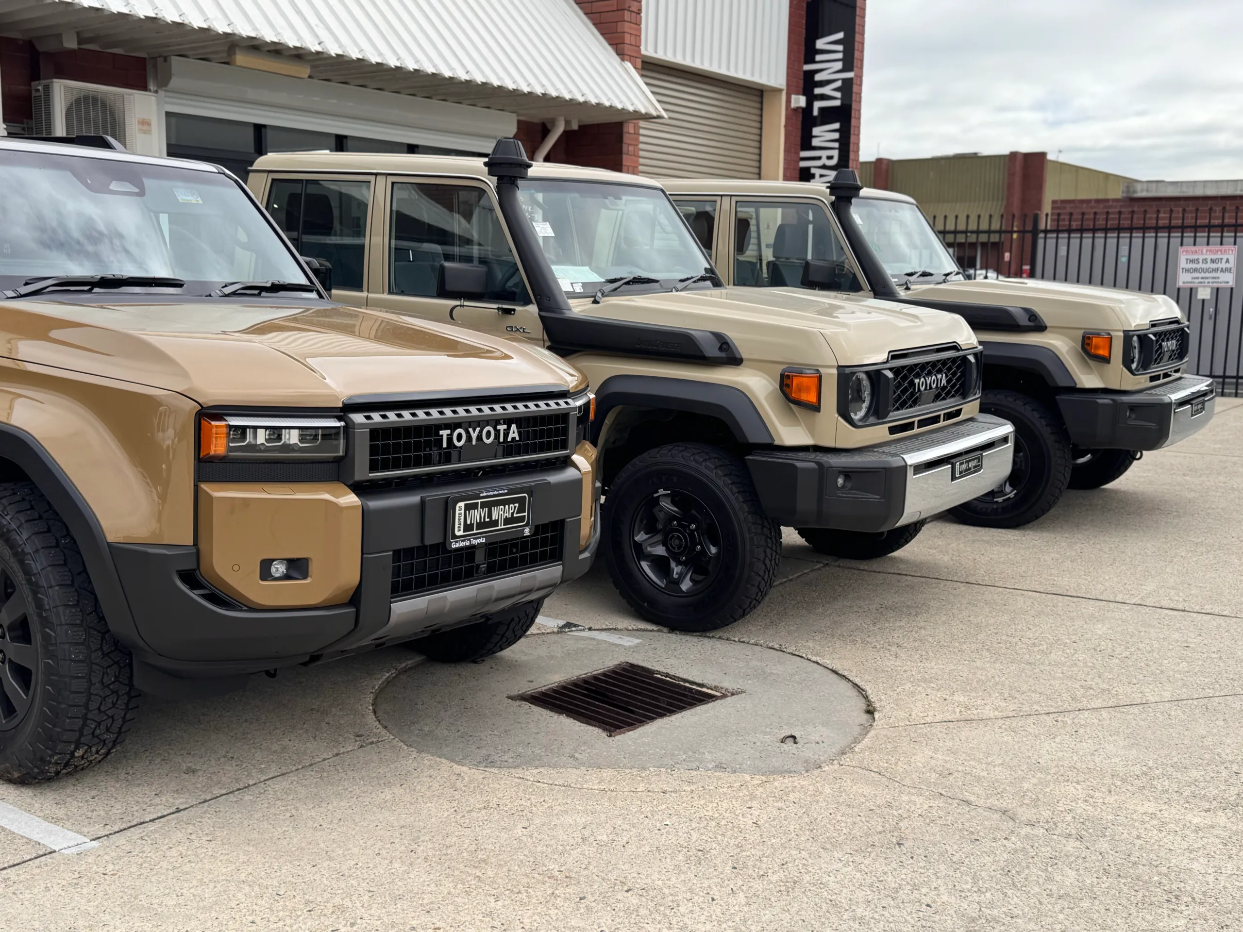Tan Toyota LandCruiser vehicles parked in a row outside Vinyl Wrapz