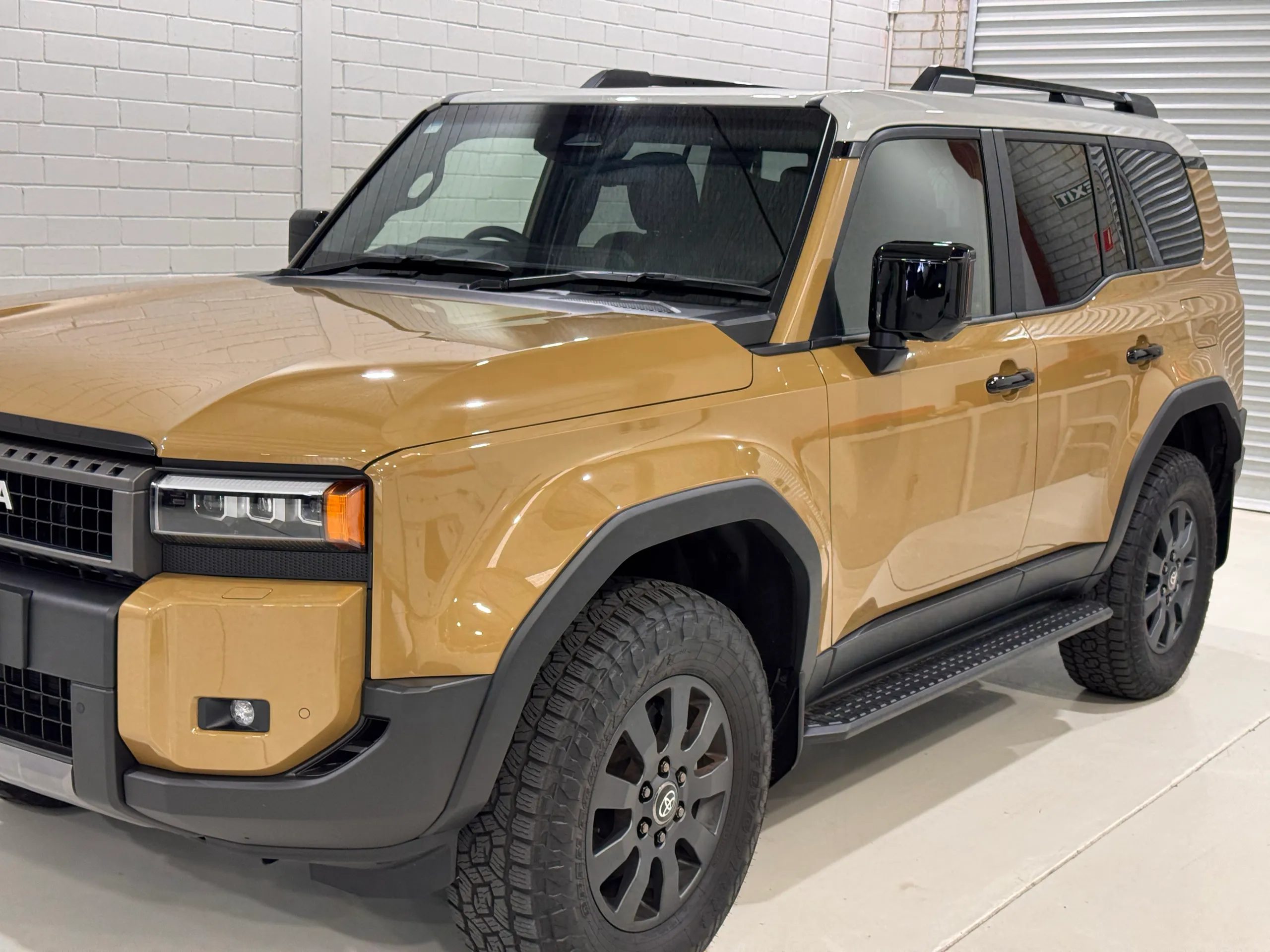 Gold Toyota LandCruiser Prado with a light roof and black trim in the workshop
