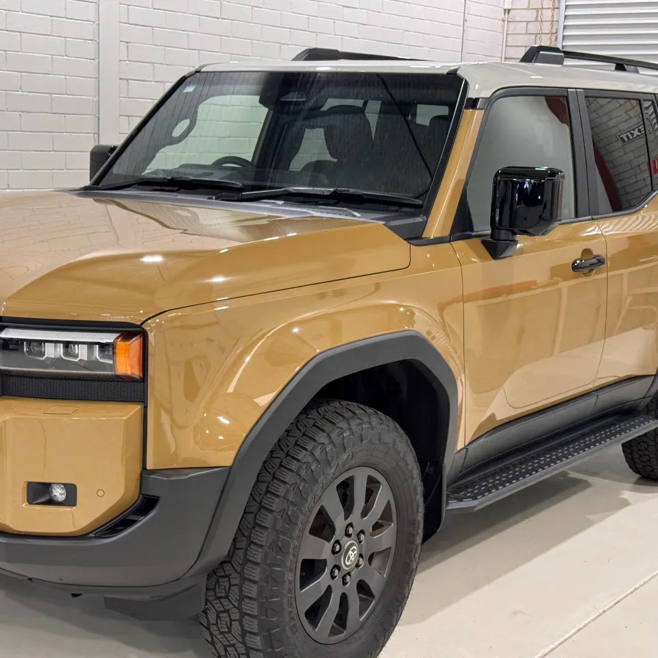 Gold Toyota LandCruiser Prado with a light roof and black trim in the workshop