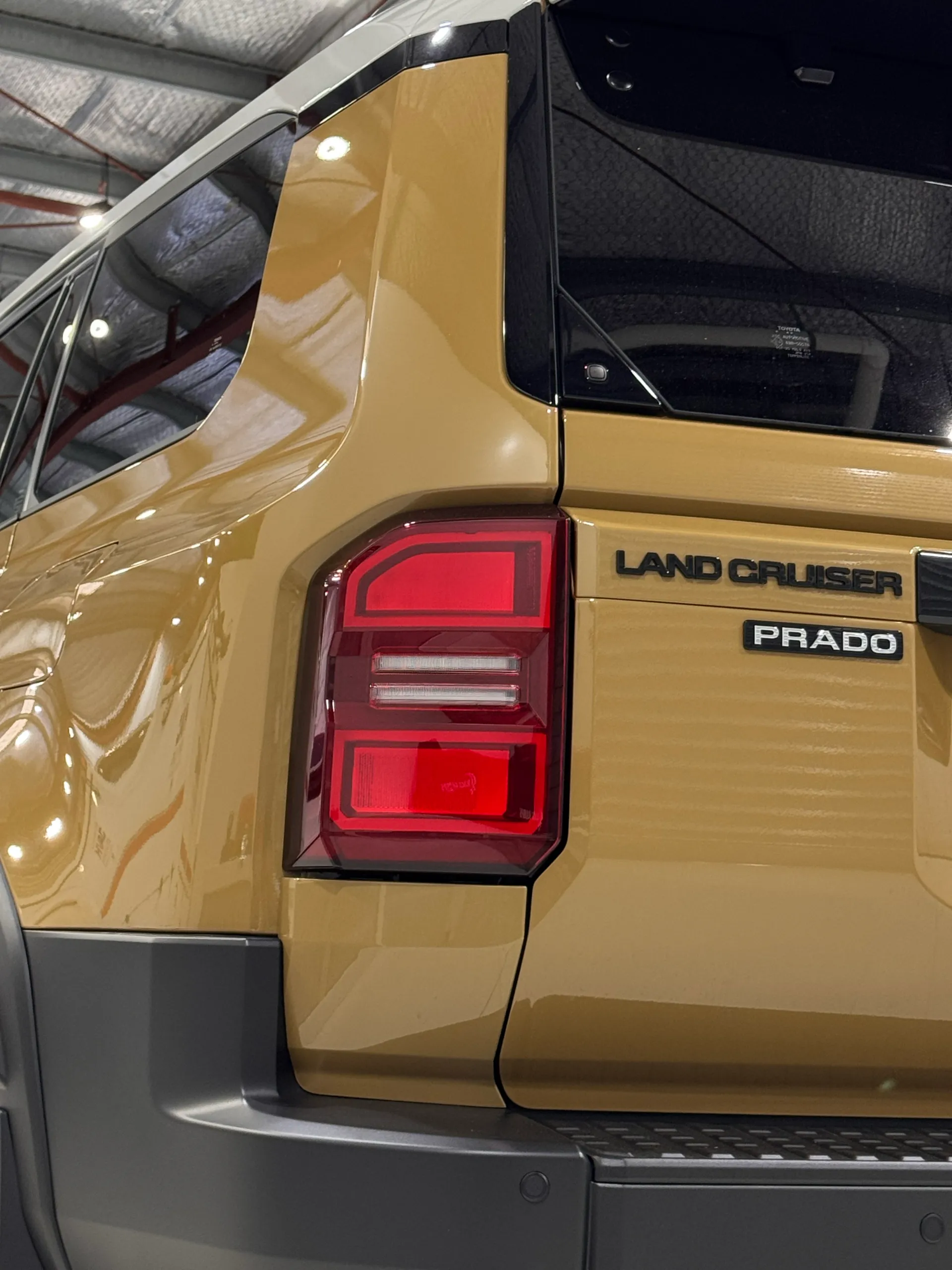 Low view of the gold Toyota LandCruiser Prado rear corner and tailgate badging