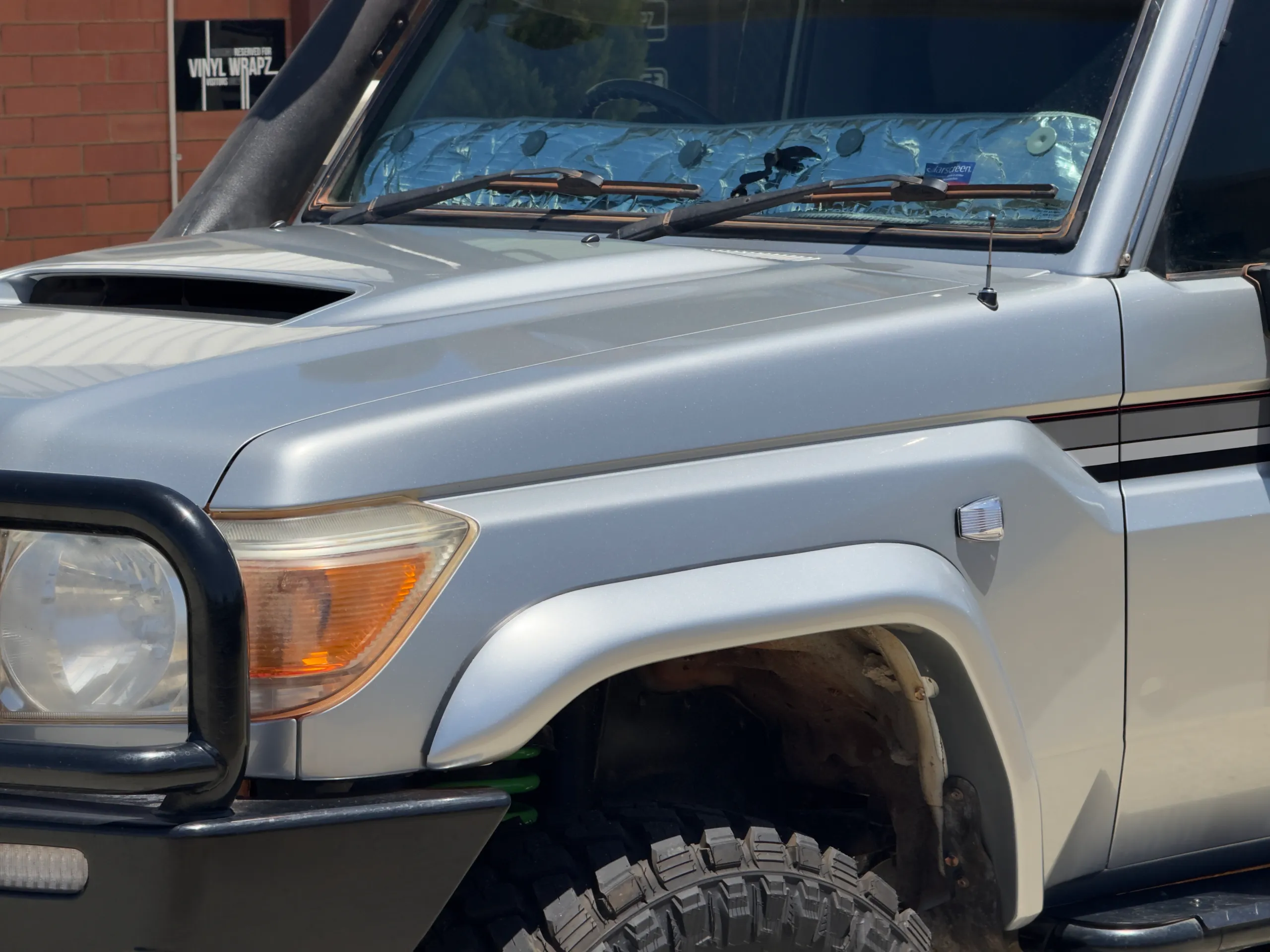 Silver Toyota LandCruiser Troop Carrier with camper roof, front detail