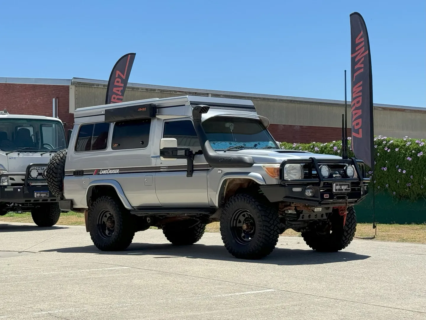 Silver Toyota LandCruiser Troop Carrier with camper roof, front quarter