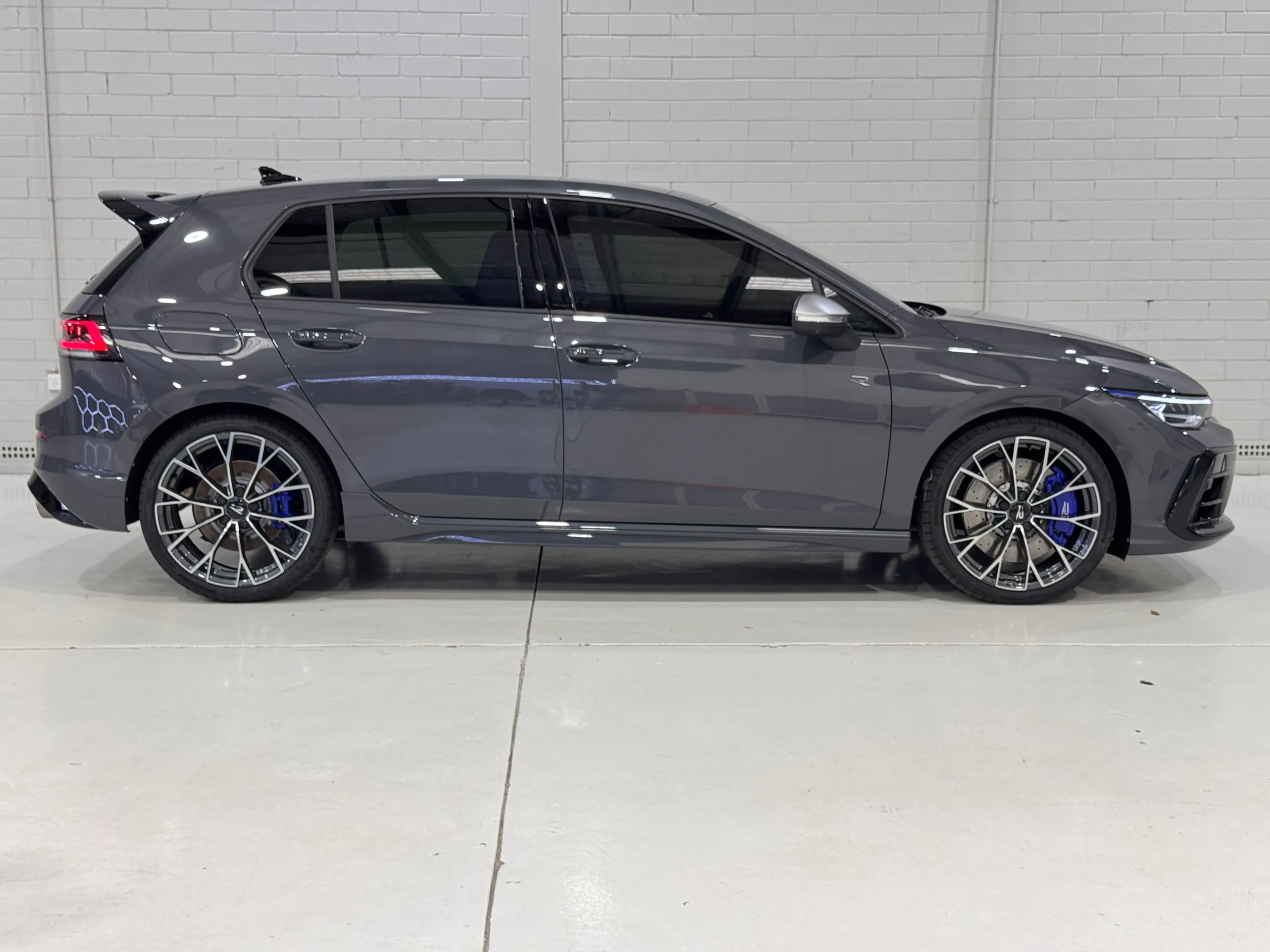 Side profile of the gloss grey Volkswagen Golf R inside the workshop