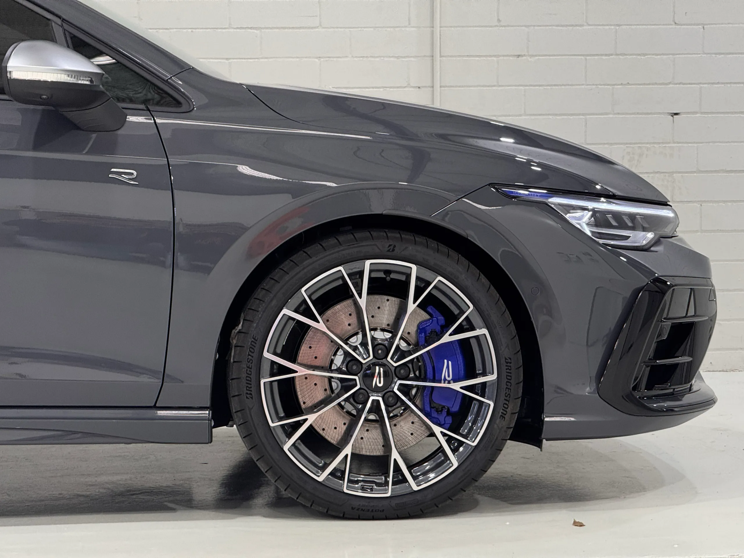 Grey Golf R front guard and wheel under workshop lighting