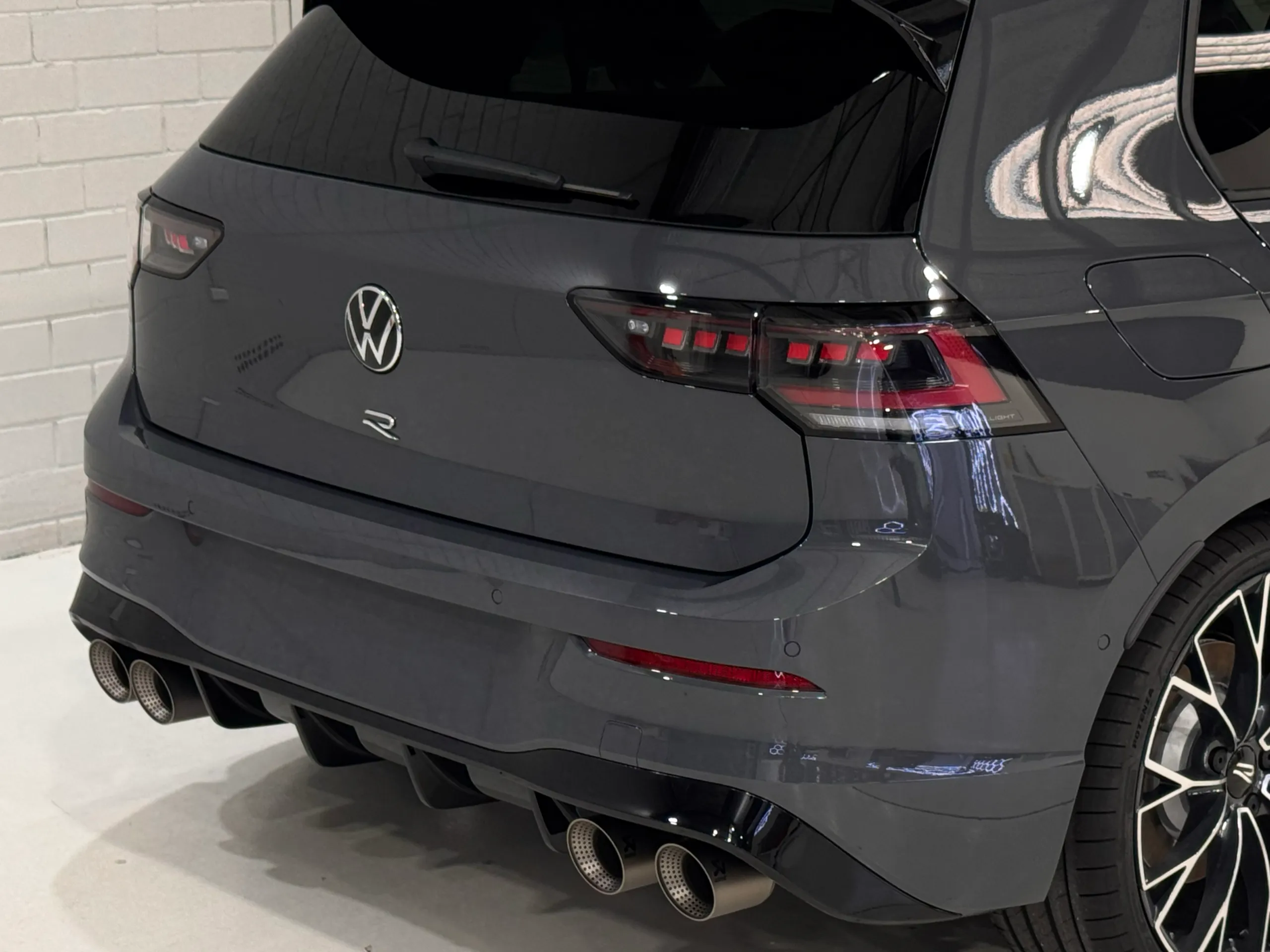 Grey Golf R rear quarter, tailgate and four exhaust tips inside the workshop