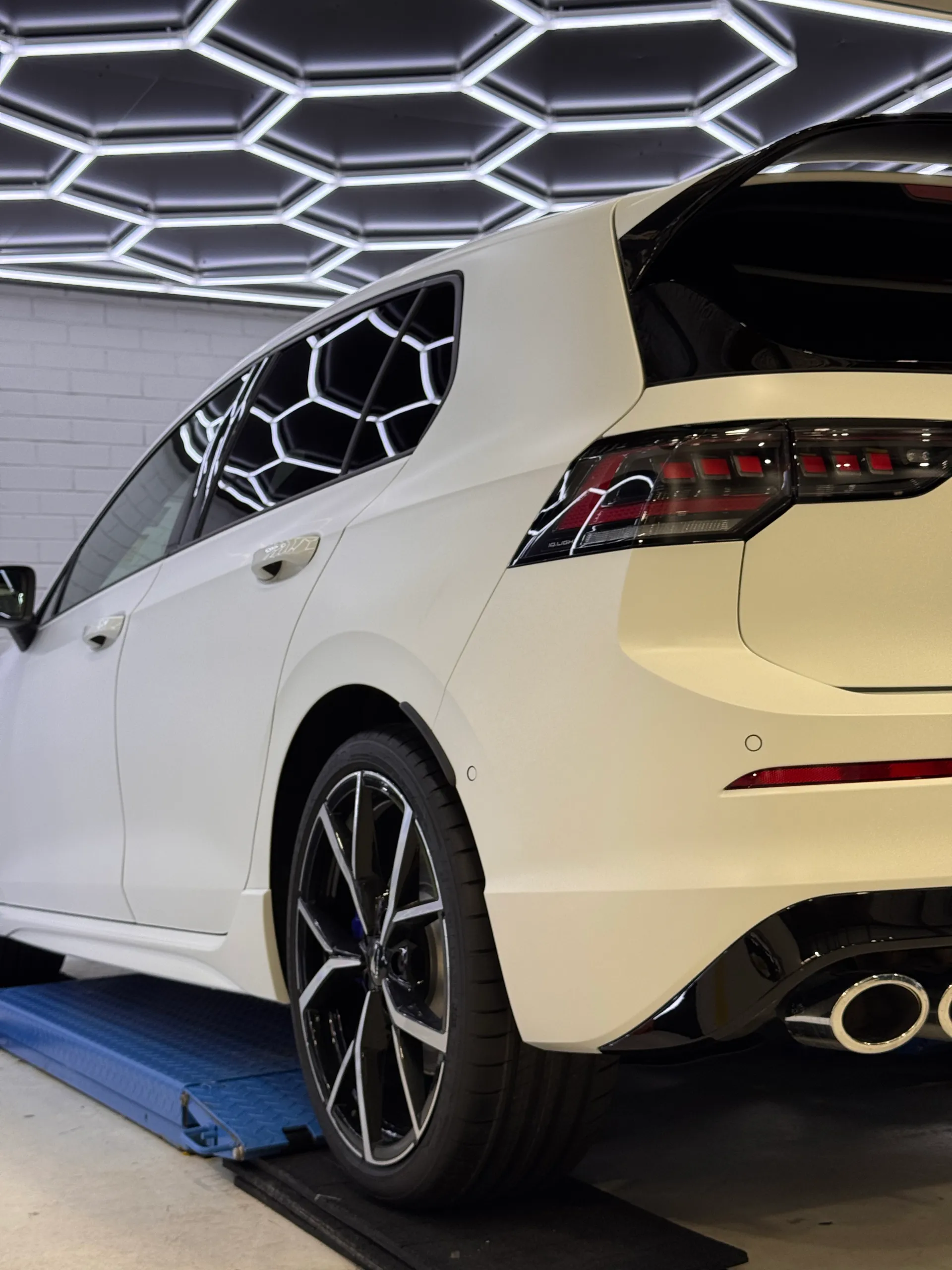 Low view of the white Golf R rear wheel, bumper and exhaust tips