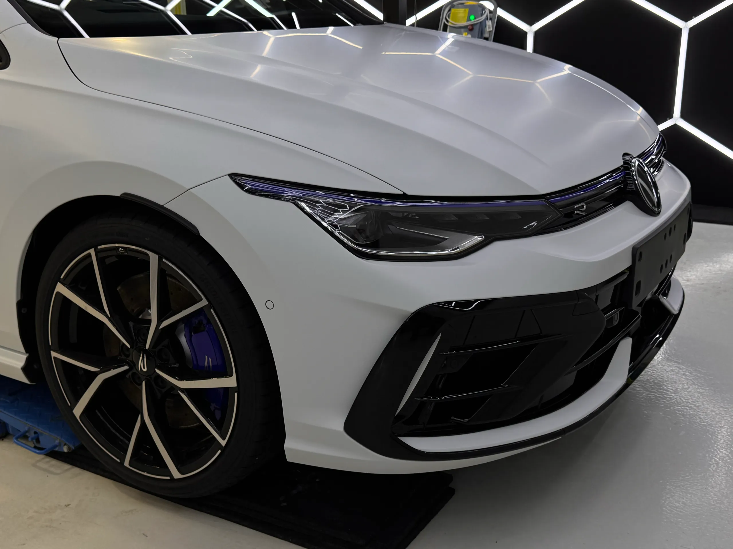 White Golf R bonnet, front wheel and grille inside the workshop