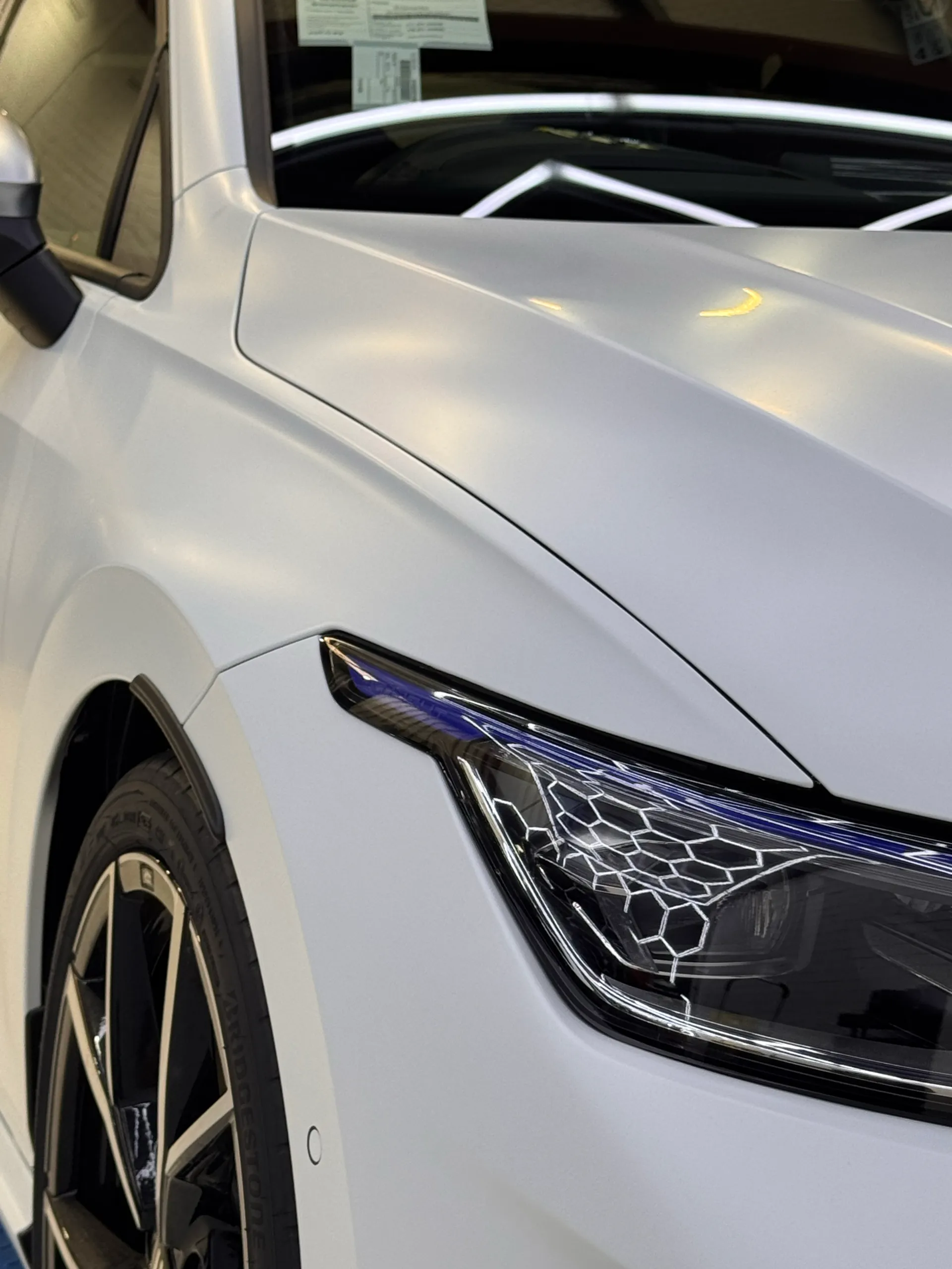 Close view of the white Golf R front guard, bonnet edge and headlight