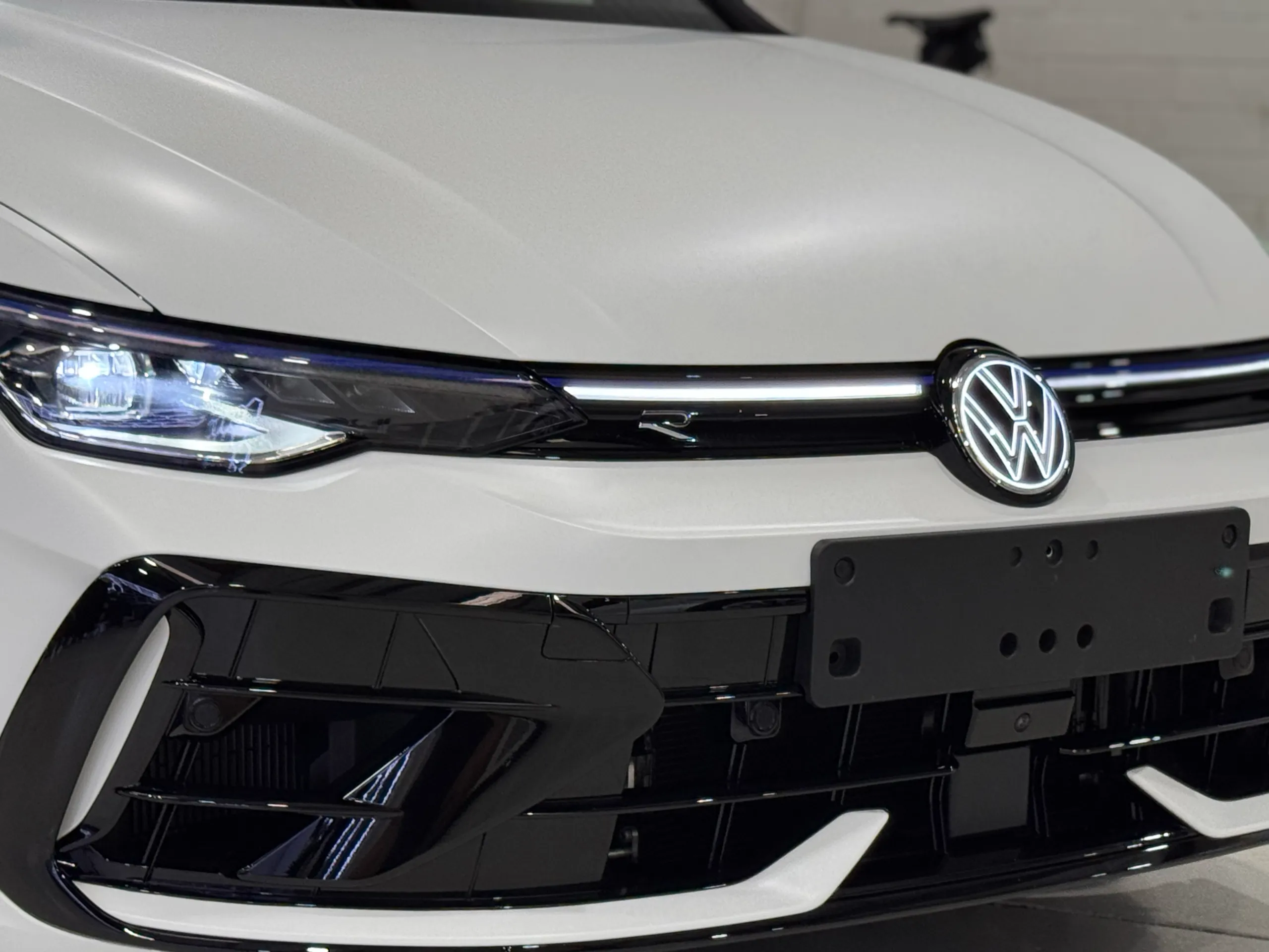 Volkswagen badge, R grille badge and headlight on the matte white Golf R