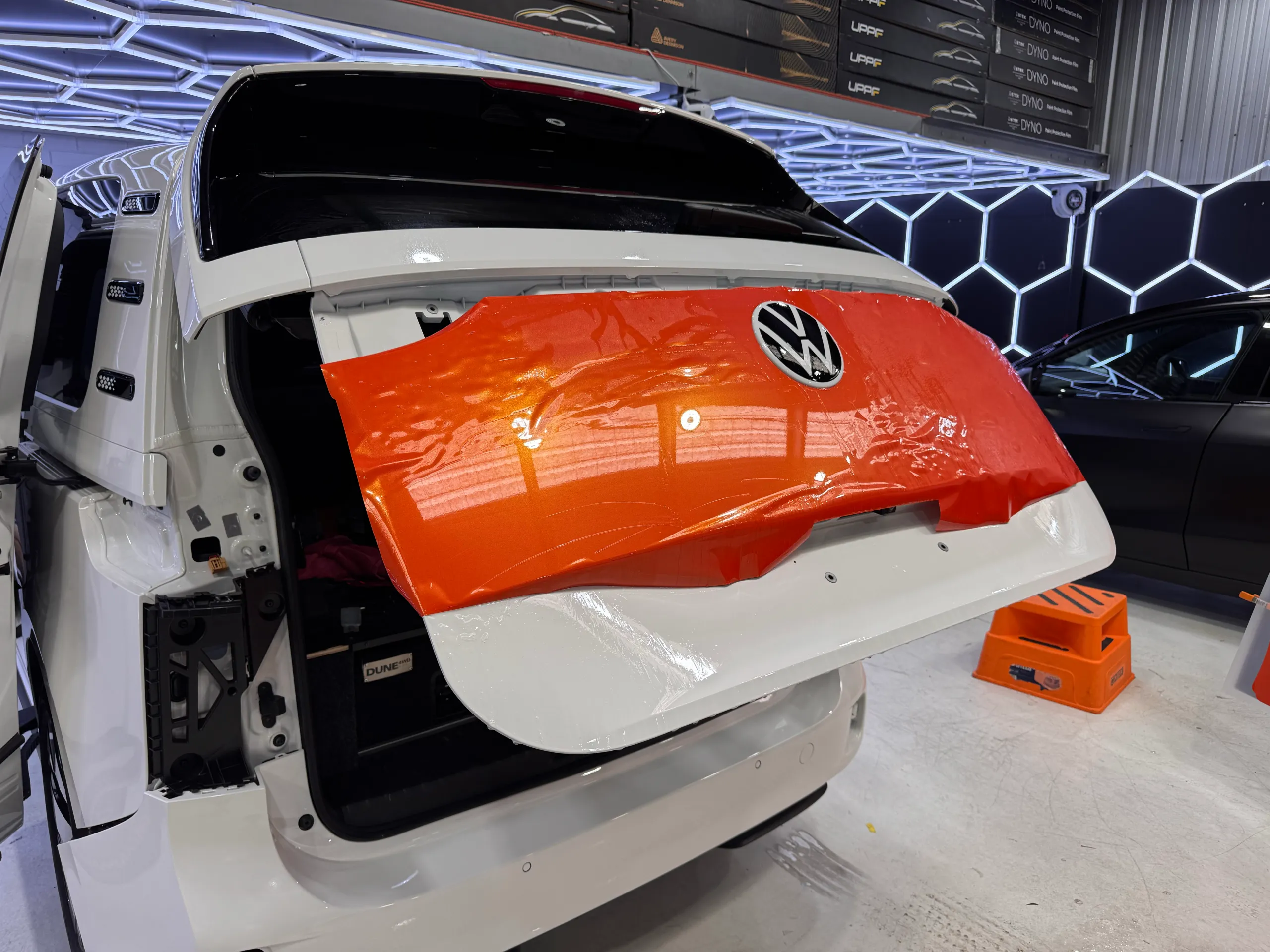 Orange film positioned over an open Volkswagen ID. Buzz tailgate during installation