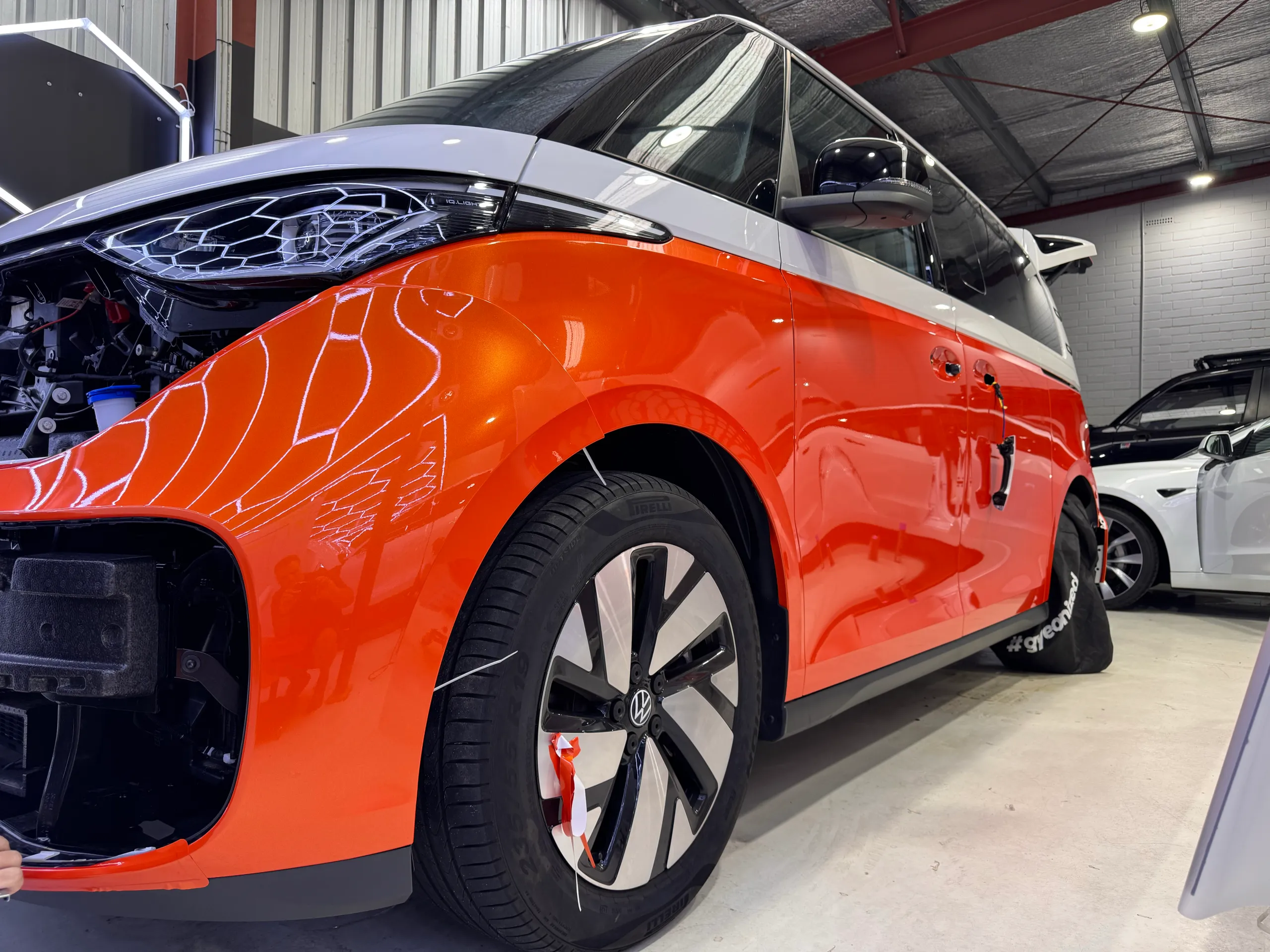 Orange and white Volkswagen ID. Buzz during wrapping, with front trim and door handles removed