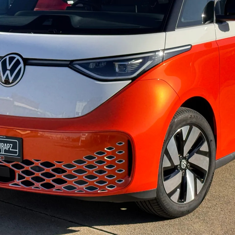 Orange and white Volkswagen ID. Buzz front quarter showing its VW emblem and Link Plumbing door logo