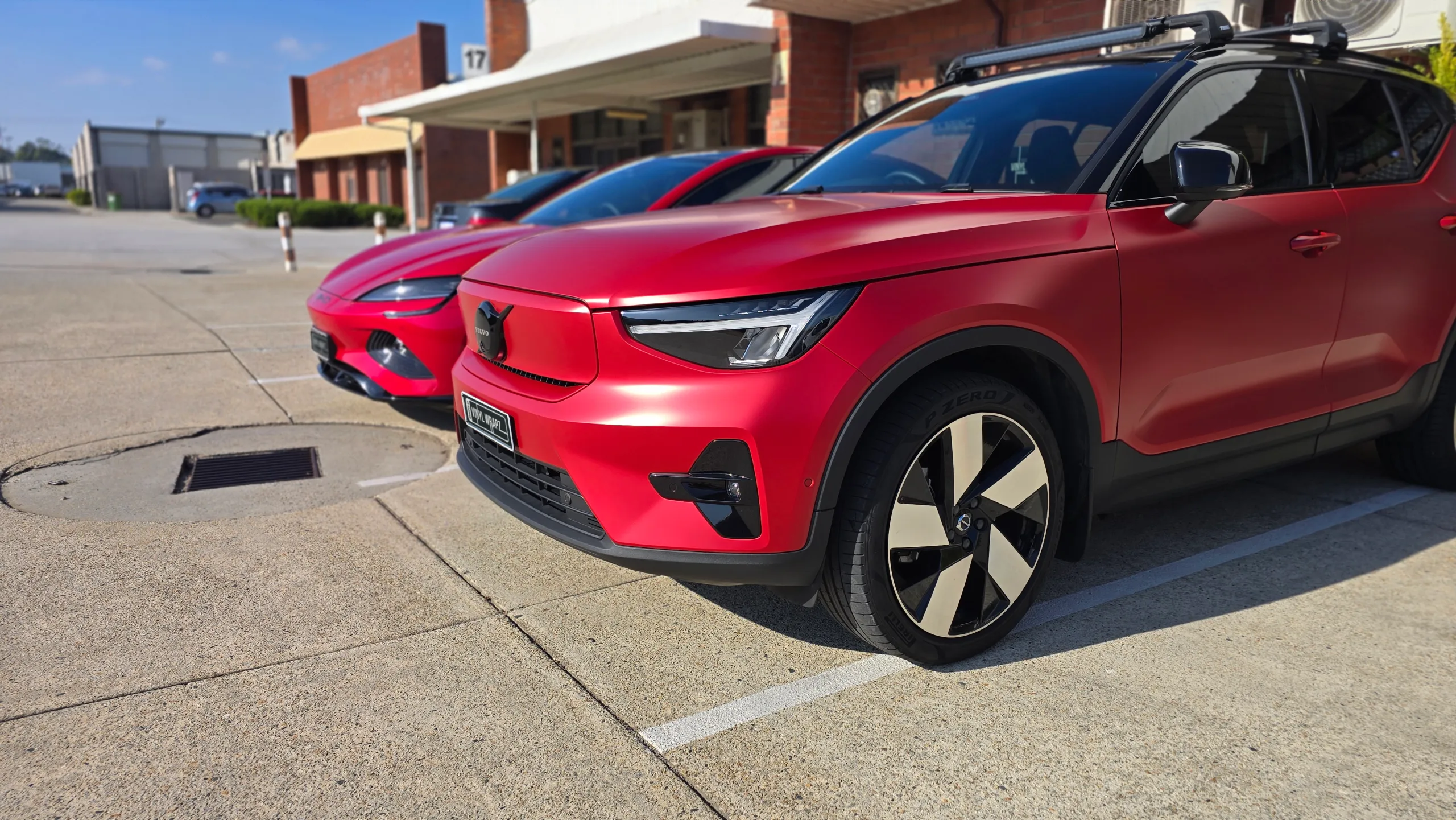 Red Volvo XC40 front quarter with a black roof and roof bars outside the workshop