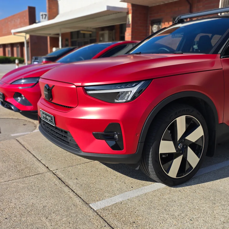 Red Volvo XC40 front quarter with a black roof and roof bars outside the workshop