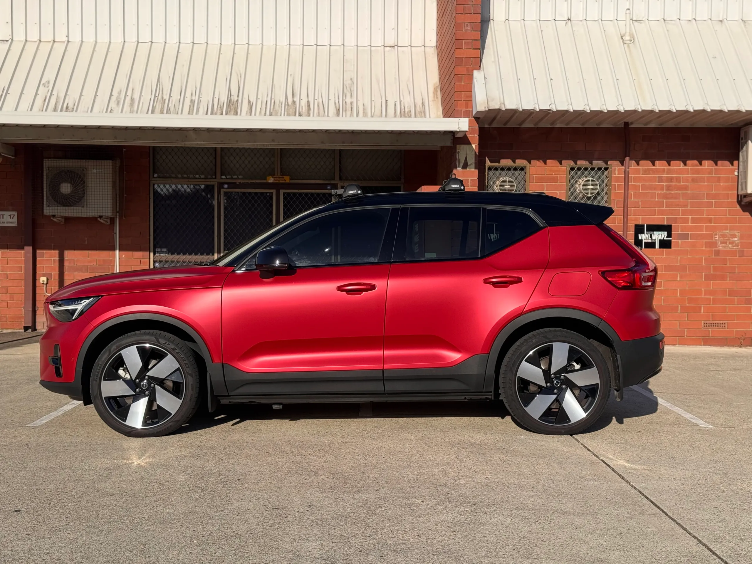 Side profile of the red Volvo XC40 with black roof and roof bars