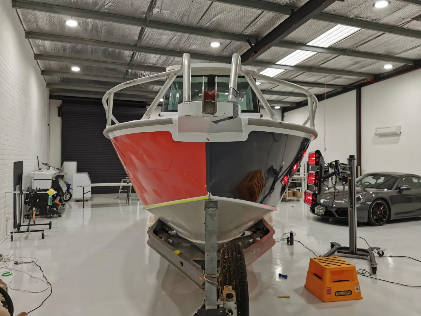 Boat bow during wrapping, with orange visible on one side and charcoal film on the other