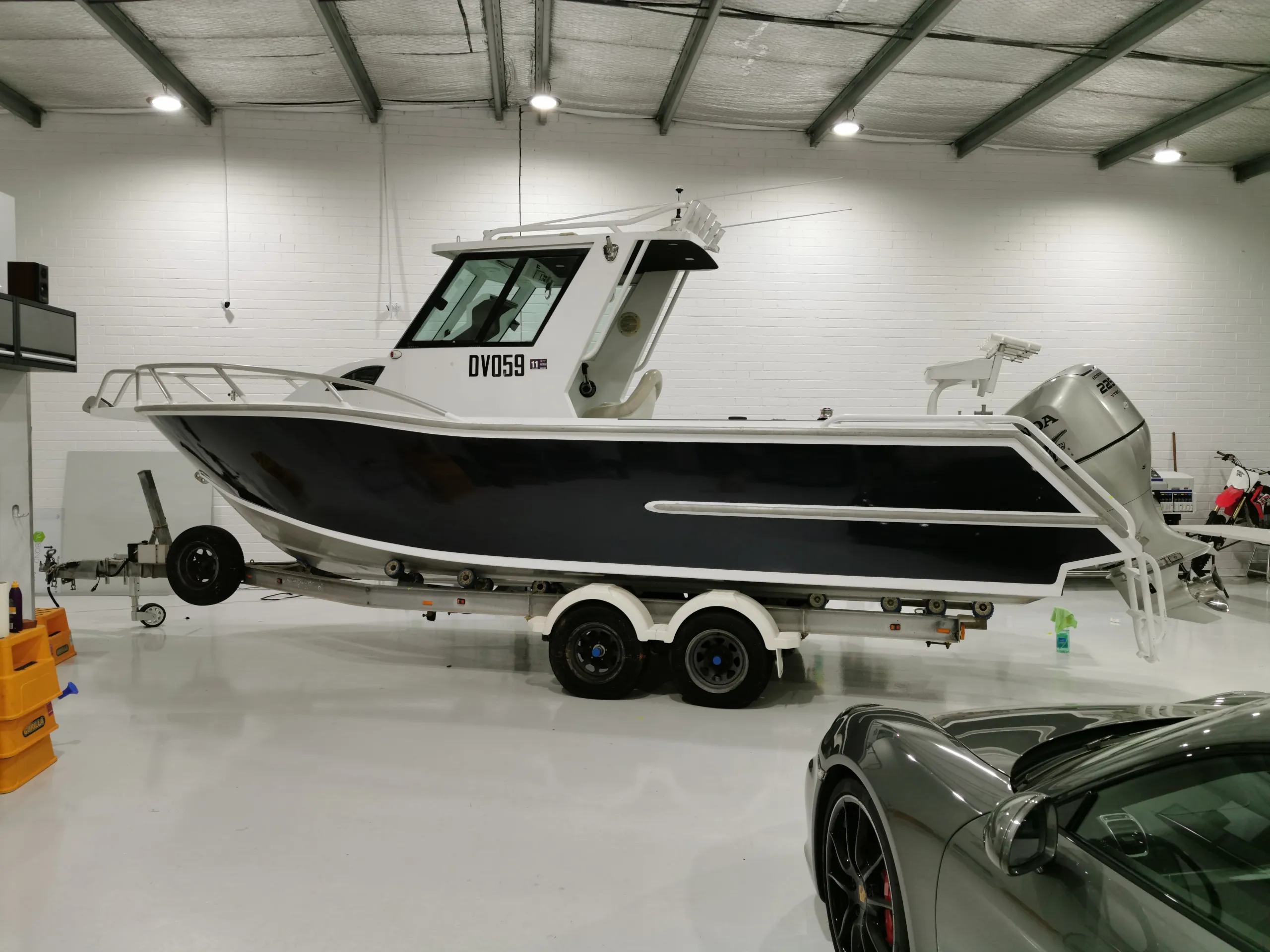 Charcoal boat with a white cabin and outboard motor on its trailer in the workshop