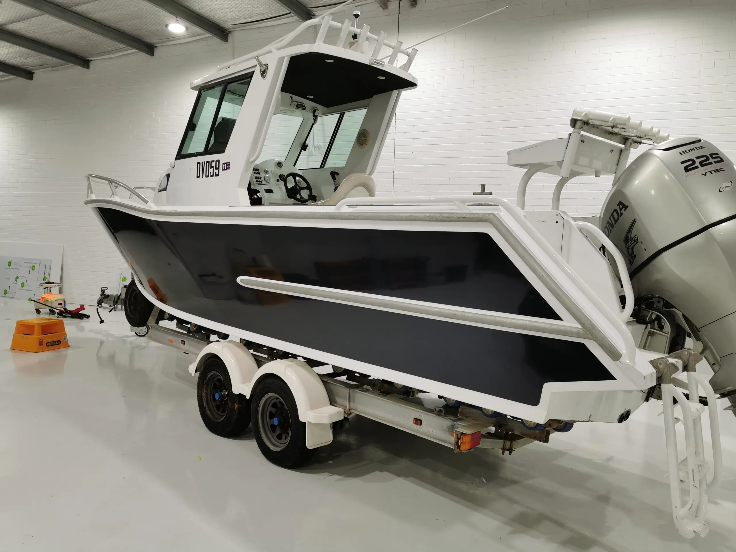 Rear-quarter view of the charcoal boat hull and outboard motor in the workshop
