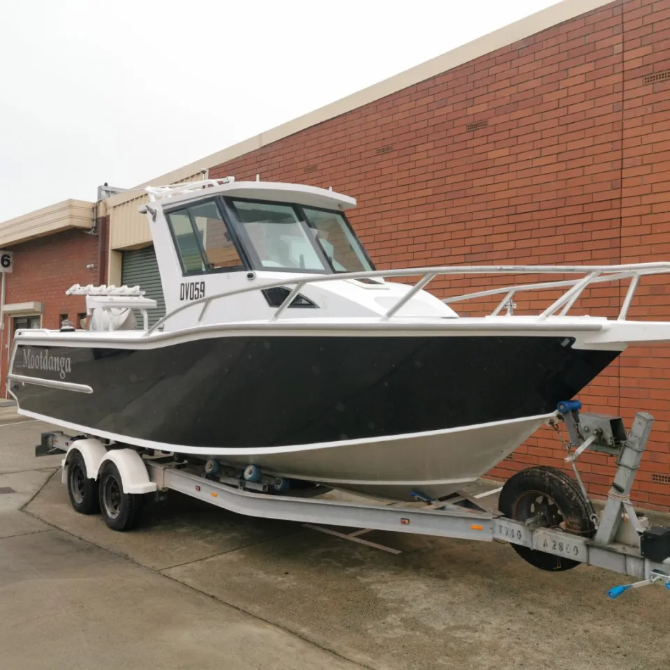 Charcoal boat with white trim on its trailer outside a brick workshop