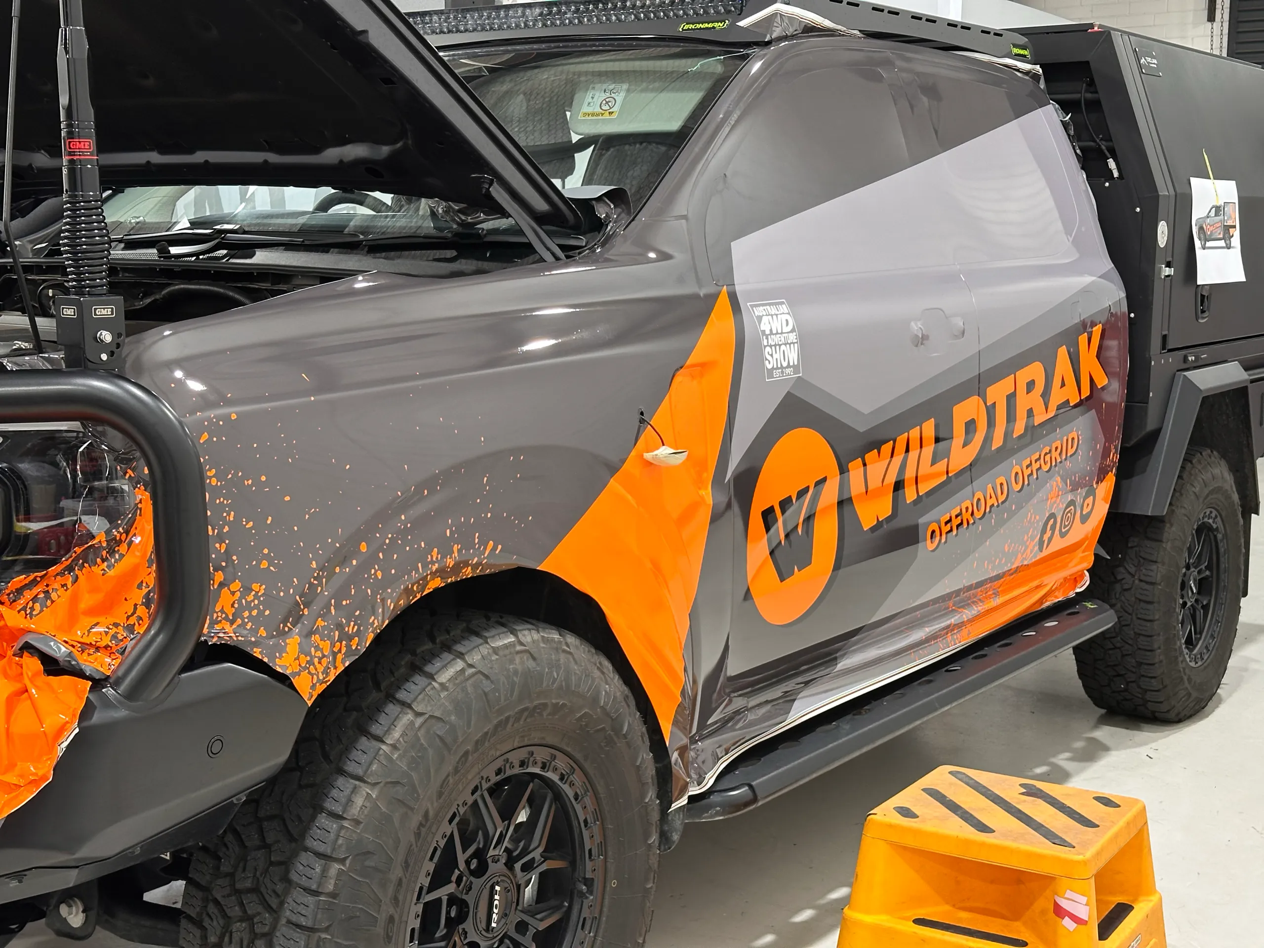 Orange and grey Wildtrak Offroad Offgrid film positioned on a Ford Ranger cab during installation