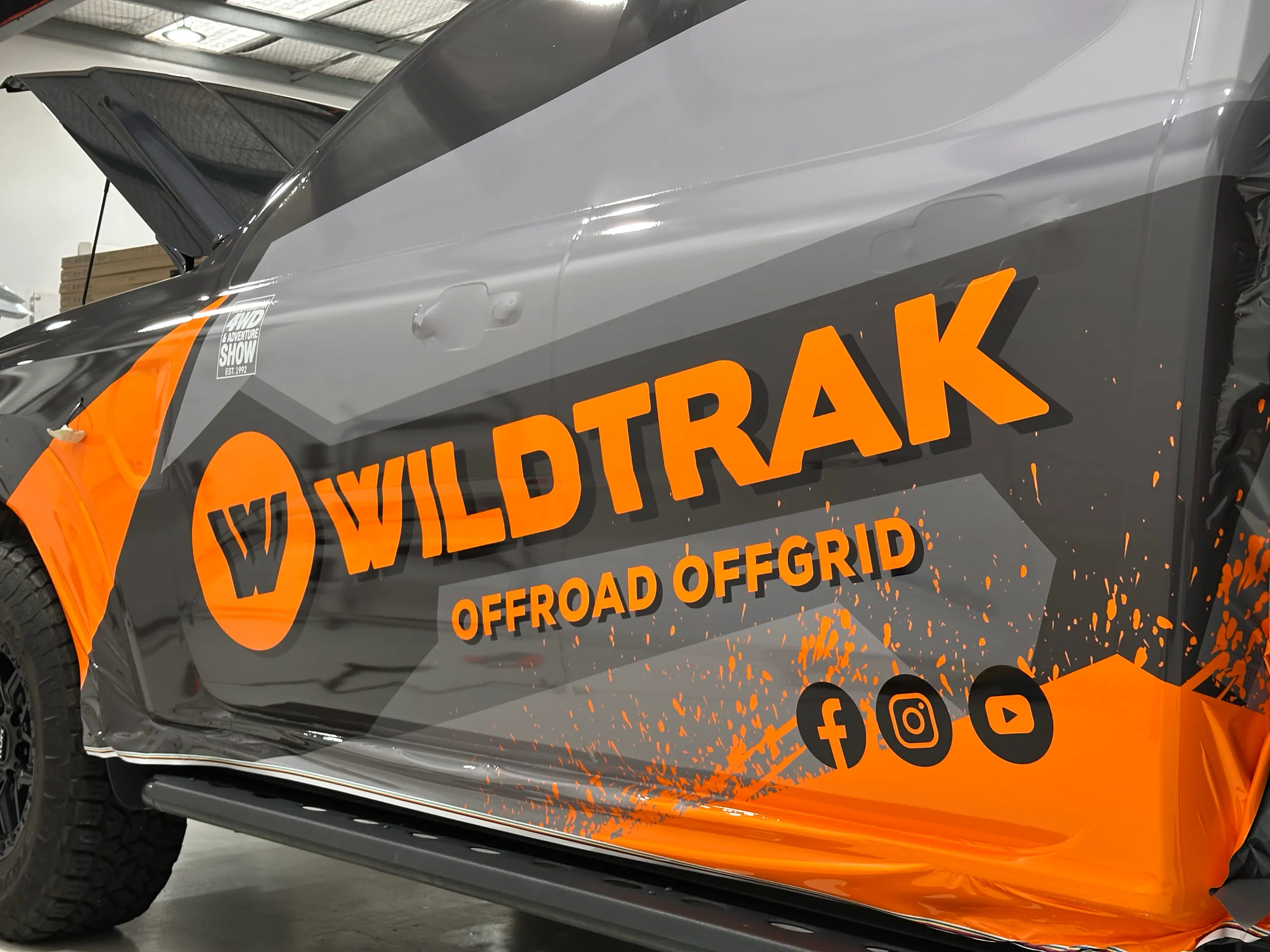 Loose orange and grey Wildtrak Offroad Offgrid film across Ford Ranger doors before trimming