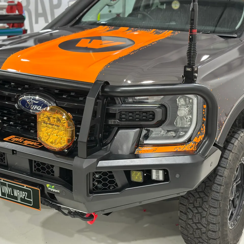 Ford Ranger front quarter with orange and grey Wildtrak graphics, a bull bar and yellow driving lights